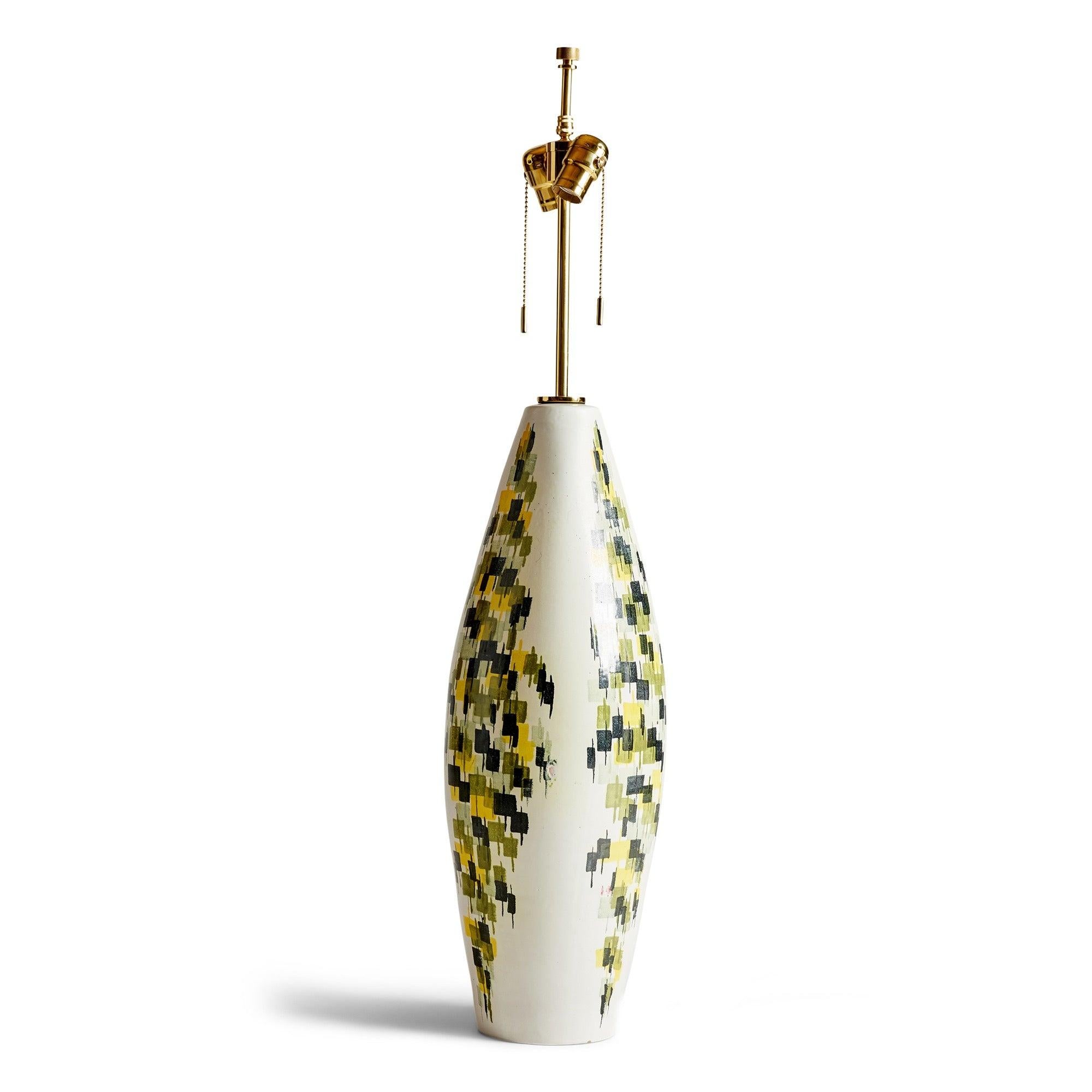 Lampe de table en céramique au fini émaillé blanc, ornée d'un motif abstrait peint à la main en vert, noir et jaune.