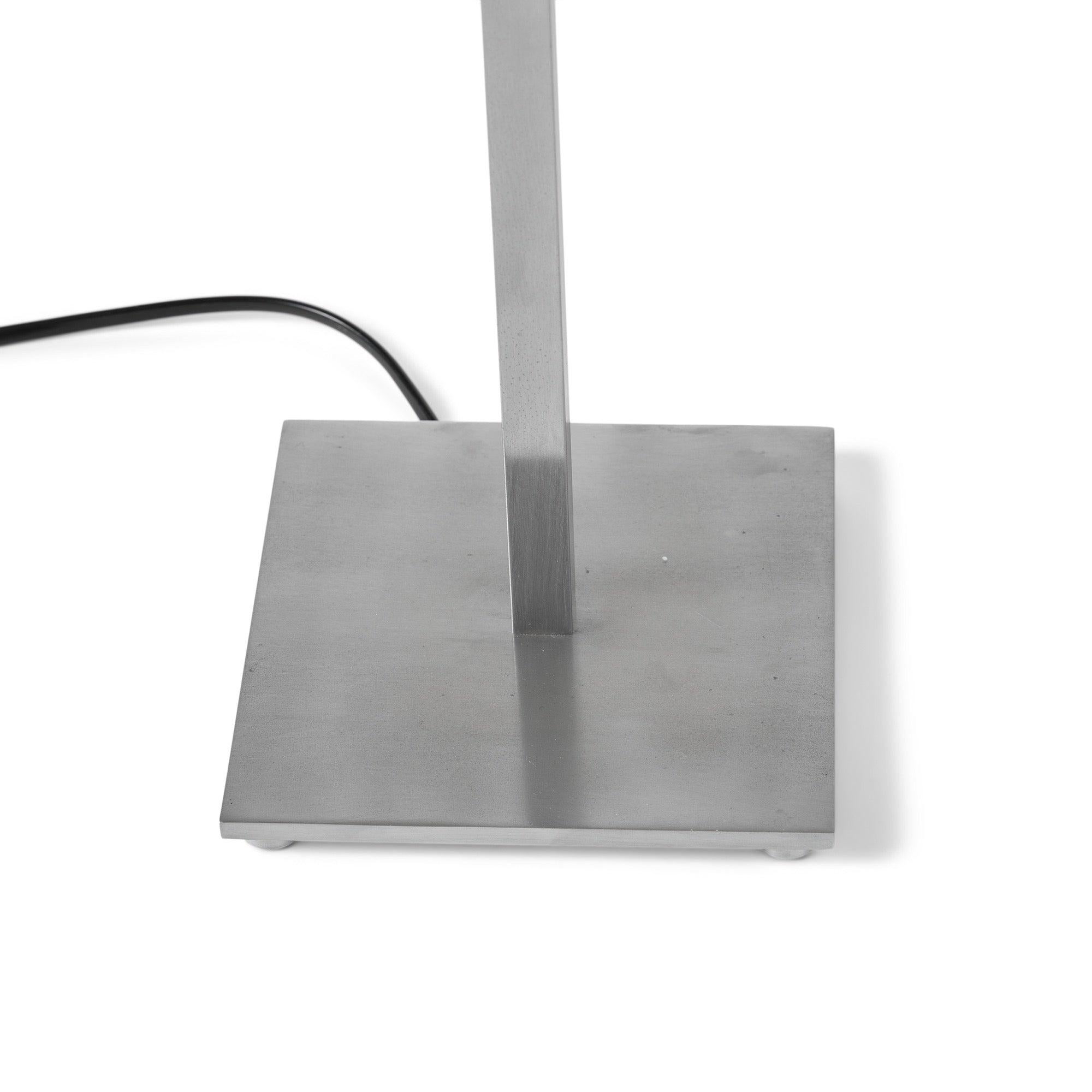 A satin nickel table lamp with a square-section stem on a square base with cylindrical feet.