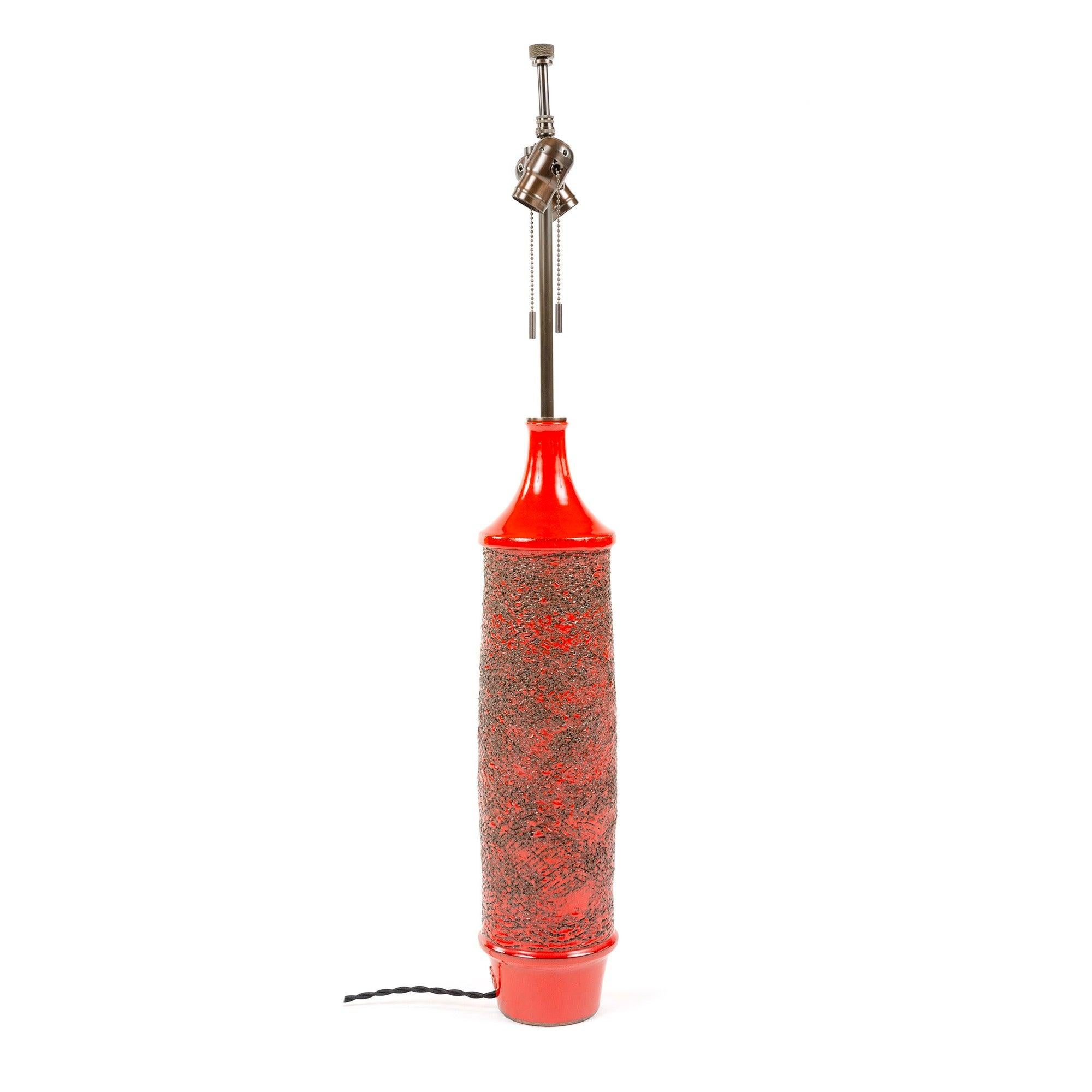 A hand-thrown cylinder-form ceramic table lamp having a rich, glossy red orange glaze and encircling deeply textured sgraffito decoration.