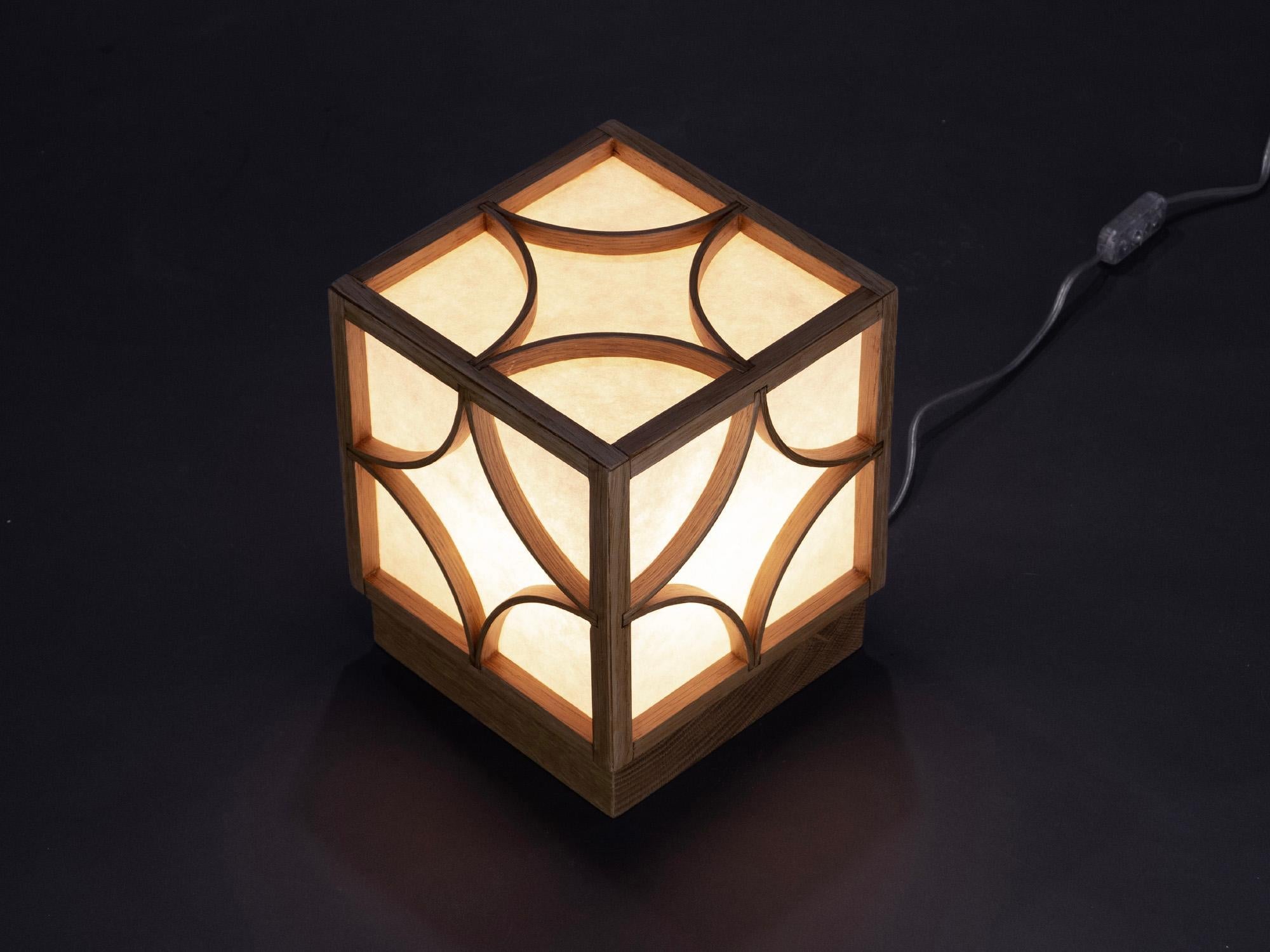 The Table Lamp is constructed from steam-bent white oak forming a cubed frame that stands on a solid white oak base. The solid white oak base can be removed easily for cleaning and bulb changing. The lamp provides a diffuse light through the