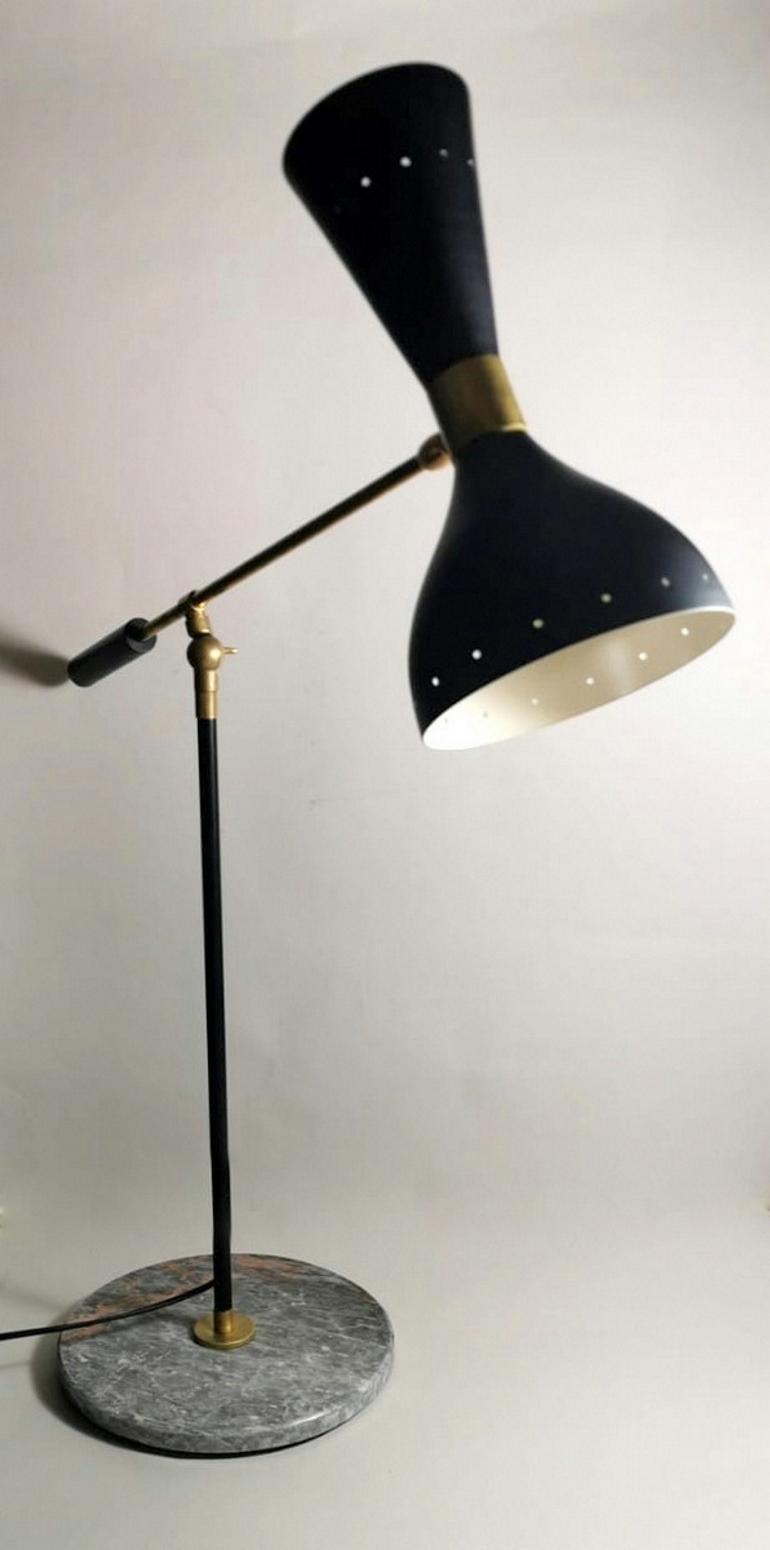 Table lamp in brass, black painted metal, cream white inside, and marble base; it has two attachments for direct and indirect light; the lamp body can rotate 360°, while the two brass bars are connected by a toothed joint that allows you to adjust