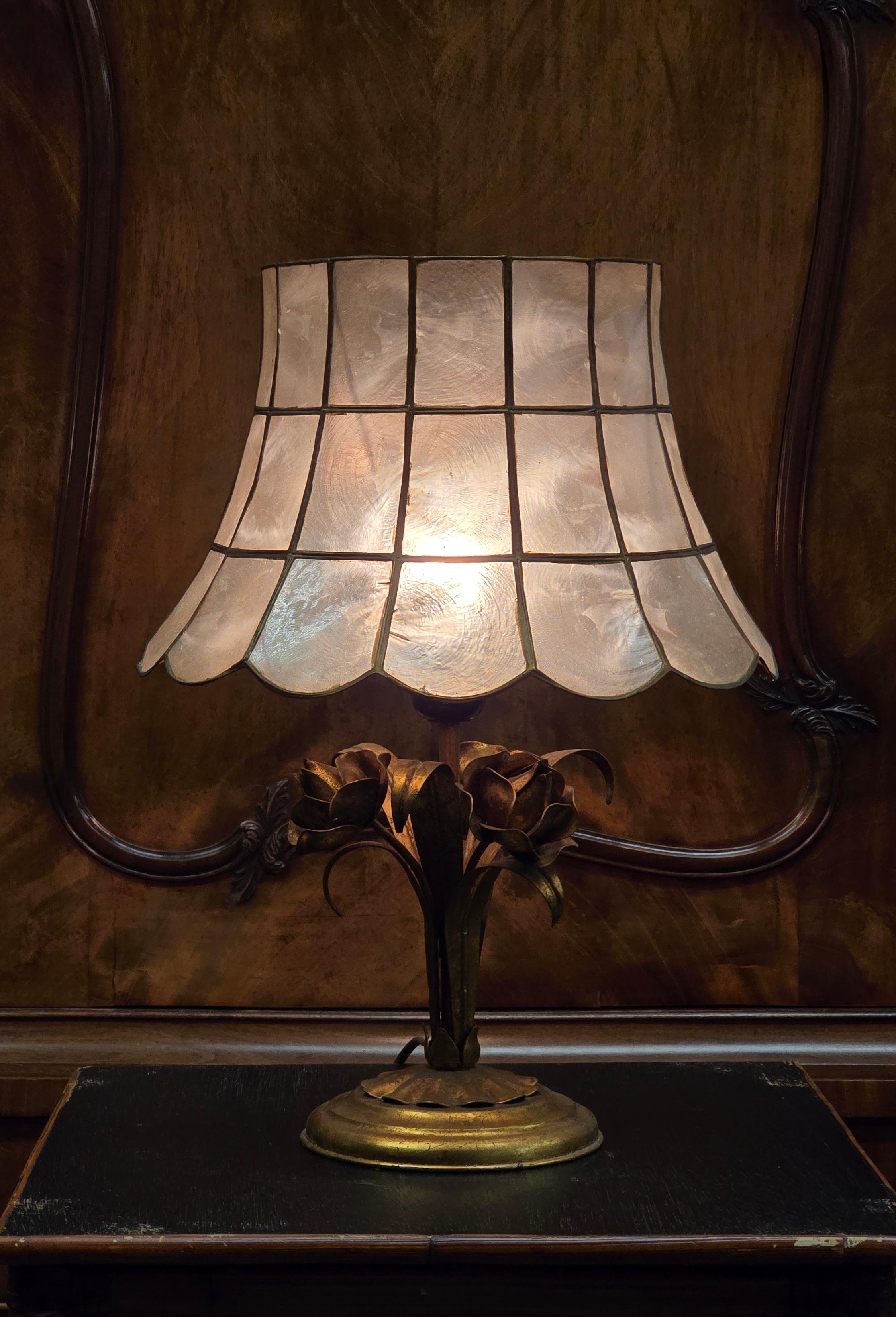 Belle lampe de table vintage des années 70 au charme unique. 
La lampe est dotée d'un socle en laiton orné d'élégantes fleurs roses et d'un abat-jour composé de magnifiques coquillages de Capiz.