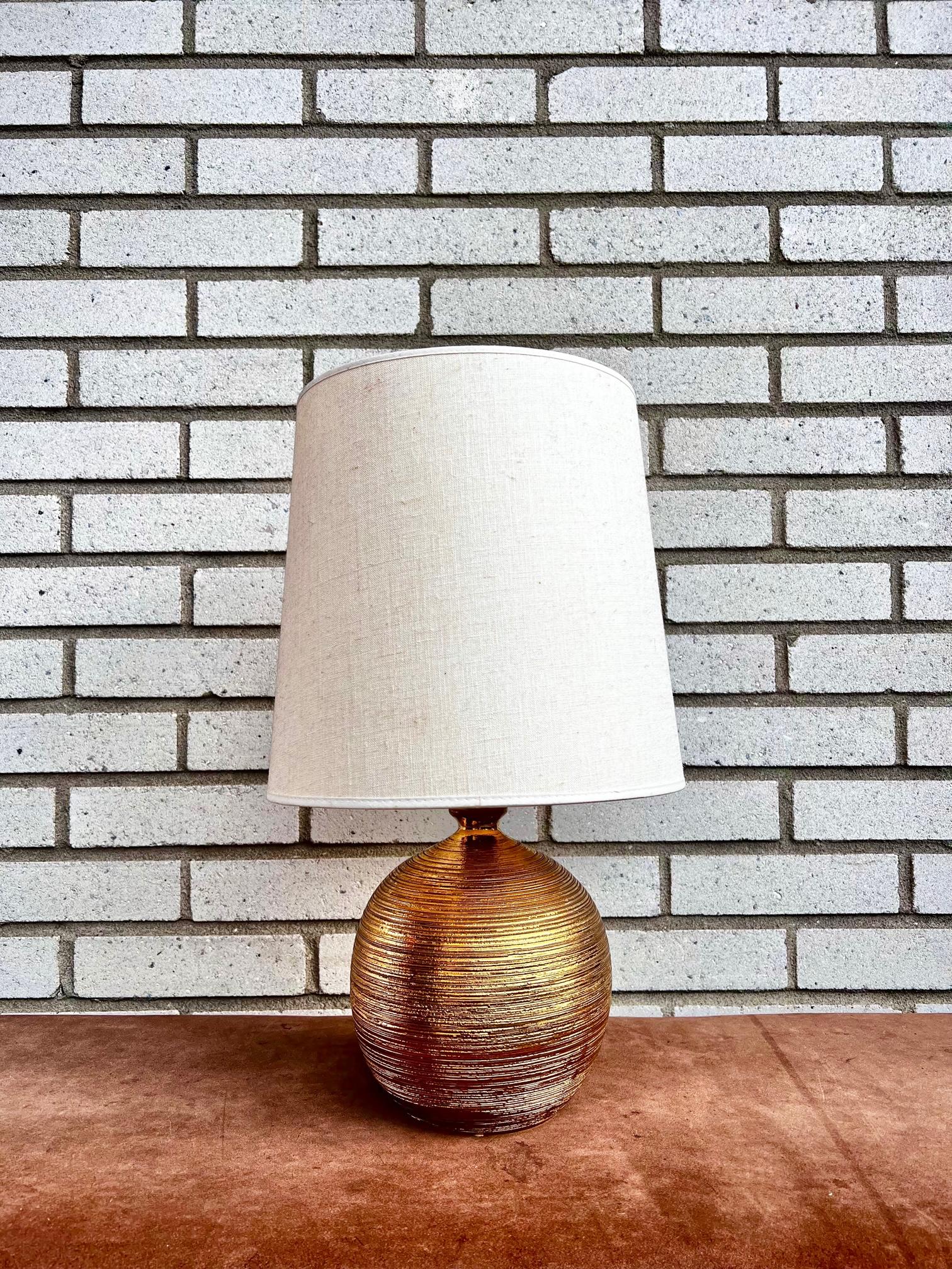 A golden glazed ceramic table lamp from 1960s. The lamp is designed by Bitossi (Italy) for Bergboms (Sweden). 

The lamp has new electricity and a older lamp shade. The lamp shade is included if wanted. 

The height is 40 cm to the socket.