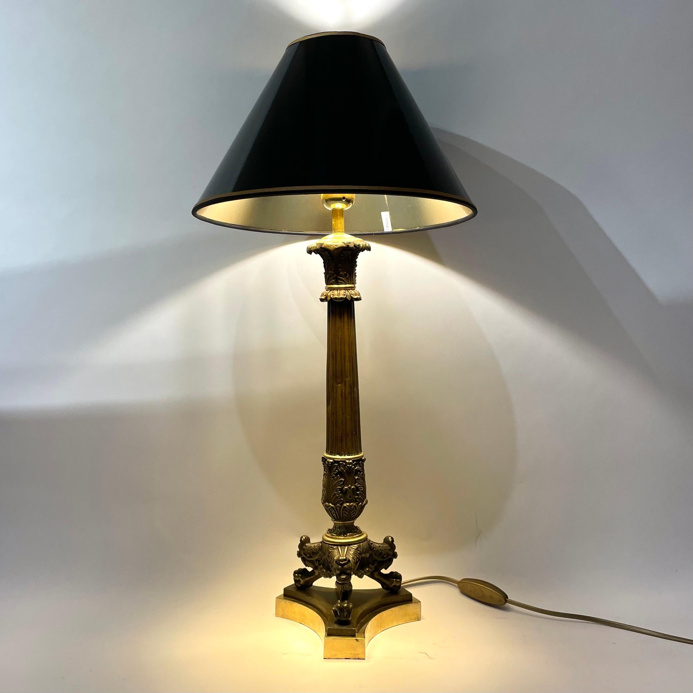 Elegante lampe de table en bronze doré et patiné foncé. Il s'agissait à l'origine d'un candélabre Empire des années 1820, transformé en lampe de table au début du 20e siècle.

L'abat-jour en laque noire avec un intérieur doré donne une lumière