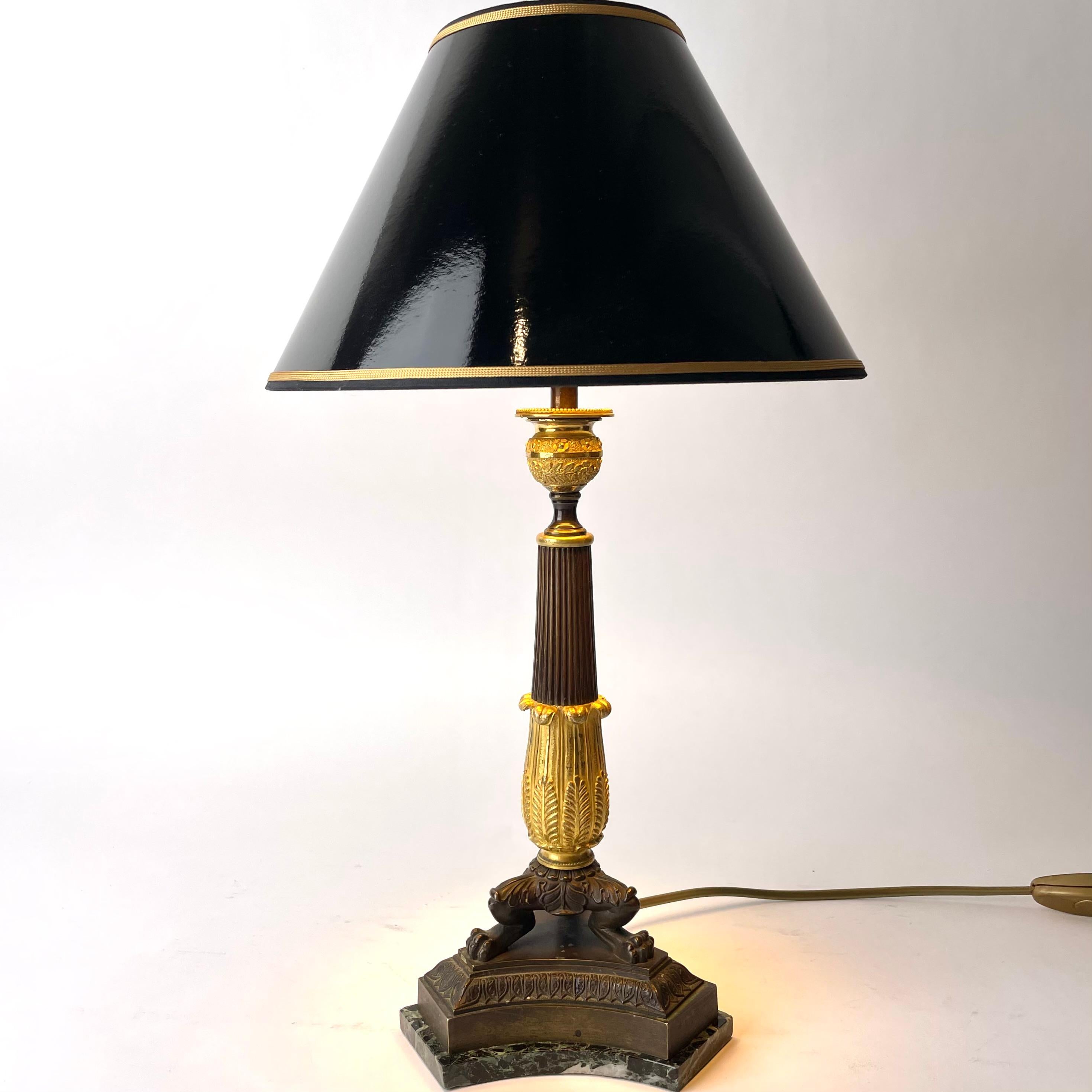 Elegante Tischleuchte aus vergoldeter und dunkel patinierter Bronze mit einem Sockel aus Marmor. Empire, entstanden in den 1820er Jahren. Ursprünglich ein Empire-Leuchter, der Anfang des 20. Jahrhunderts in eine Tischlampe umgewandelt wurde.

Neu