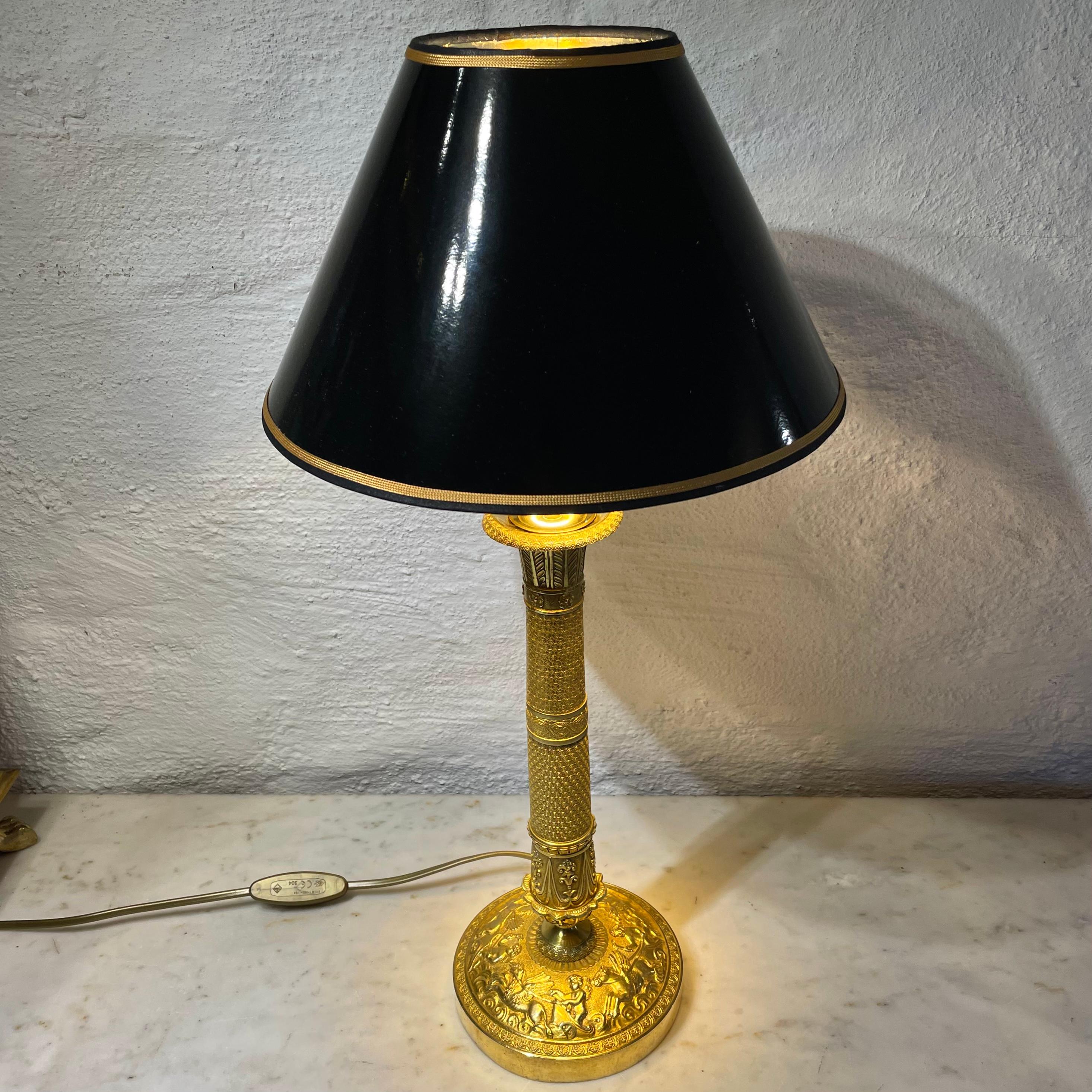 An elegant table lamp in gilded bronze. Originally an Empire Candlestick from the 1820s, converted into a table lamp during the 20th century.

The lampshade in black lacquer with a gilded inside to give a cozy light.

New rewired