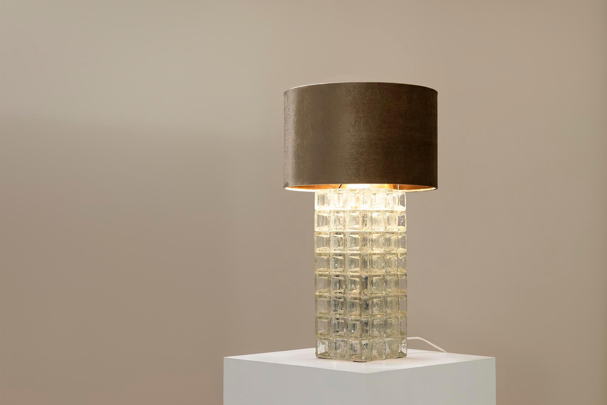 Cette lampe de table peut être décrite comme élégante avec la classe d'un design intemporel. L'artiste verrier italien Albano Steele est à l'origine de cette création, faite de verre et surmontée d'une fixation métallique en acier brossé.Ce qui est