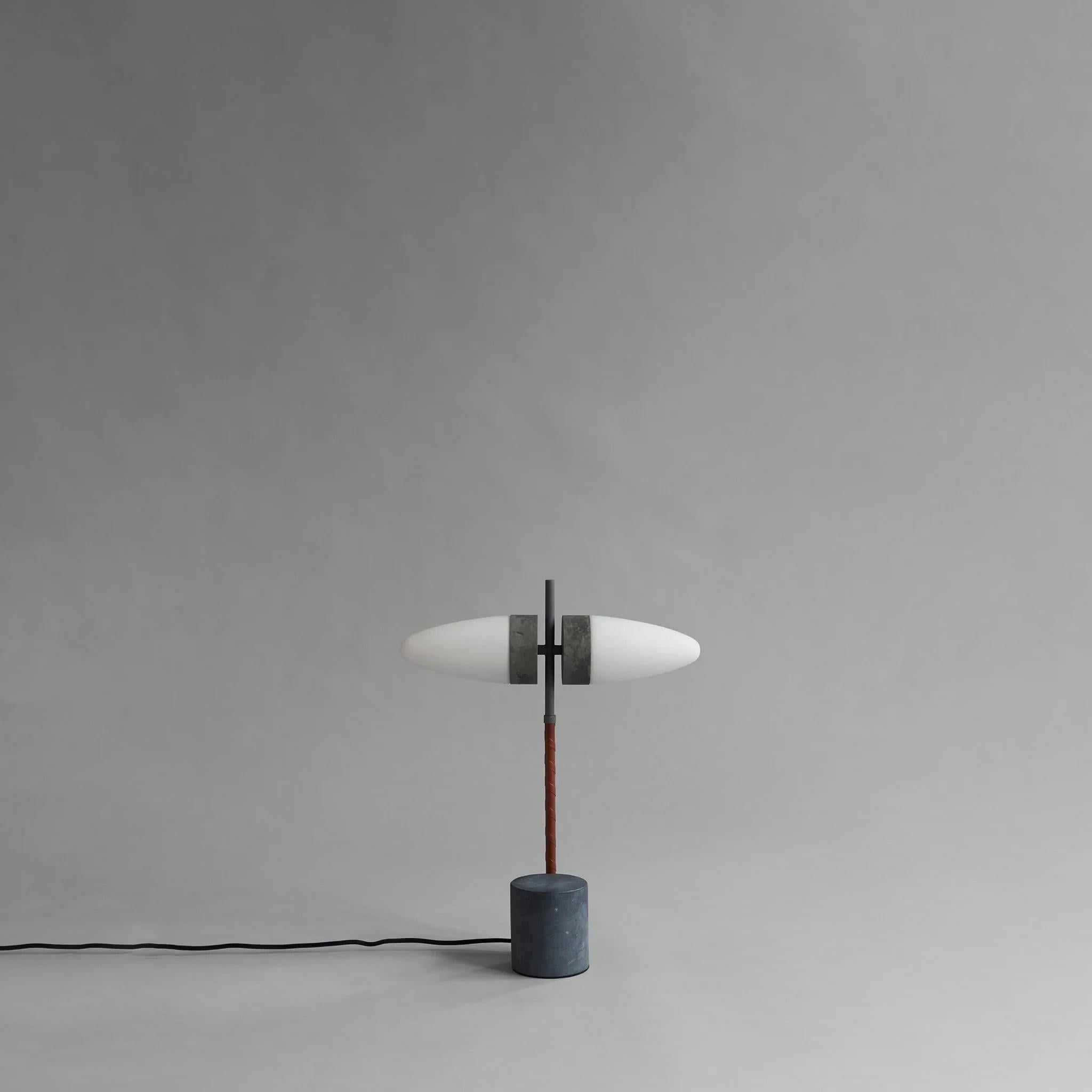 Lampe de table en métal oxydé et verre opale, œuvre contemporaine.
 
Inspiré par l'utilisation caractéristique de l'imagerie animale dans le modernisme danois des années 1940 à 1960, il tire son nom des abat-jours en verre opale en forme de taureau.