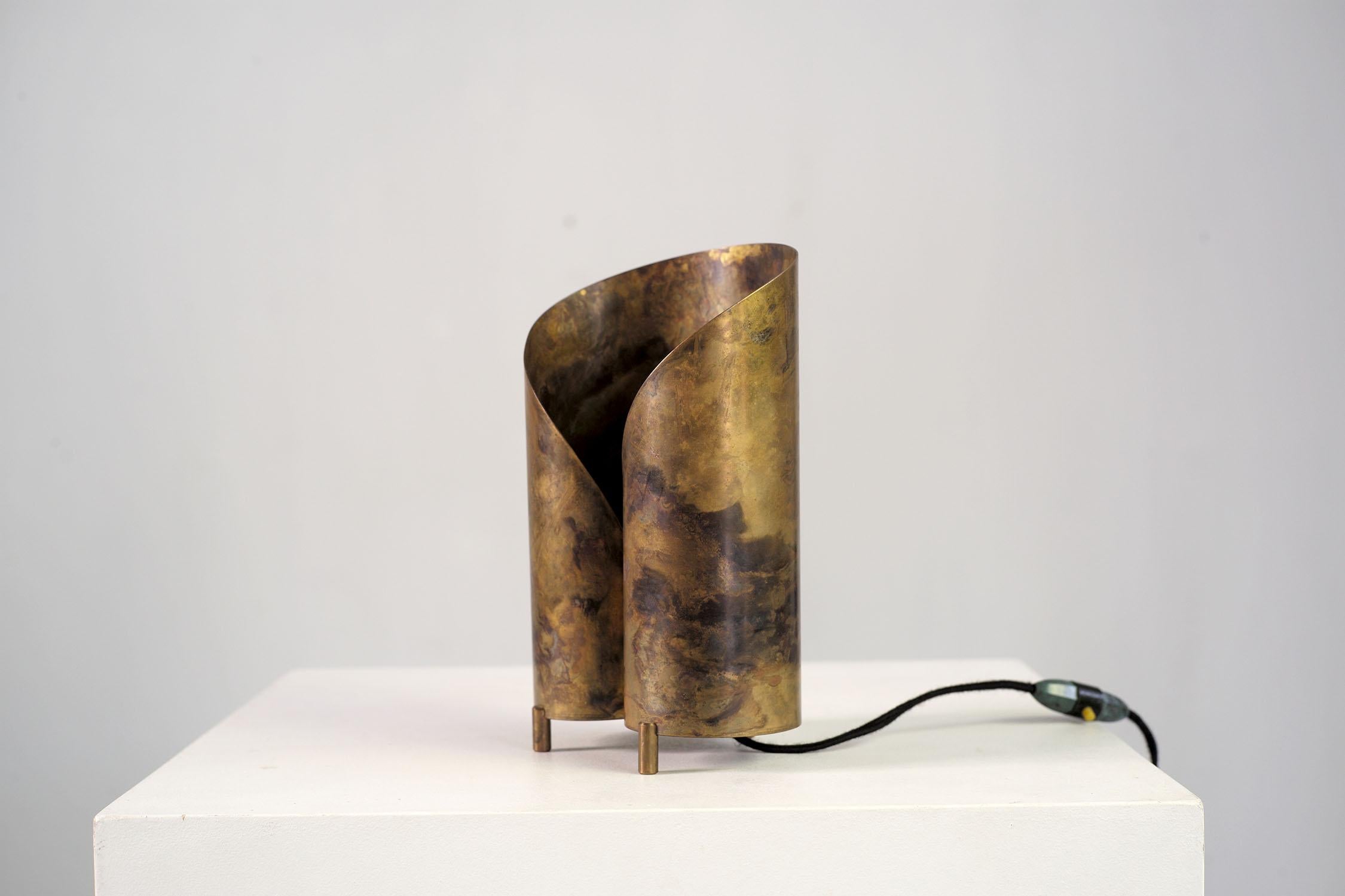 Lampe tripode en laiton oxydé et vernis, France 1950.
Cette lampe est raffinée dans ses moindres détails, la feuille de métal s'enroule, formant deux lobes. La patine du bronze est le résultat d'un travail avec un pad rempli d'acide, ce qui confère