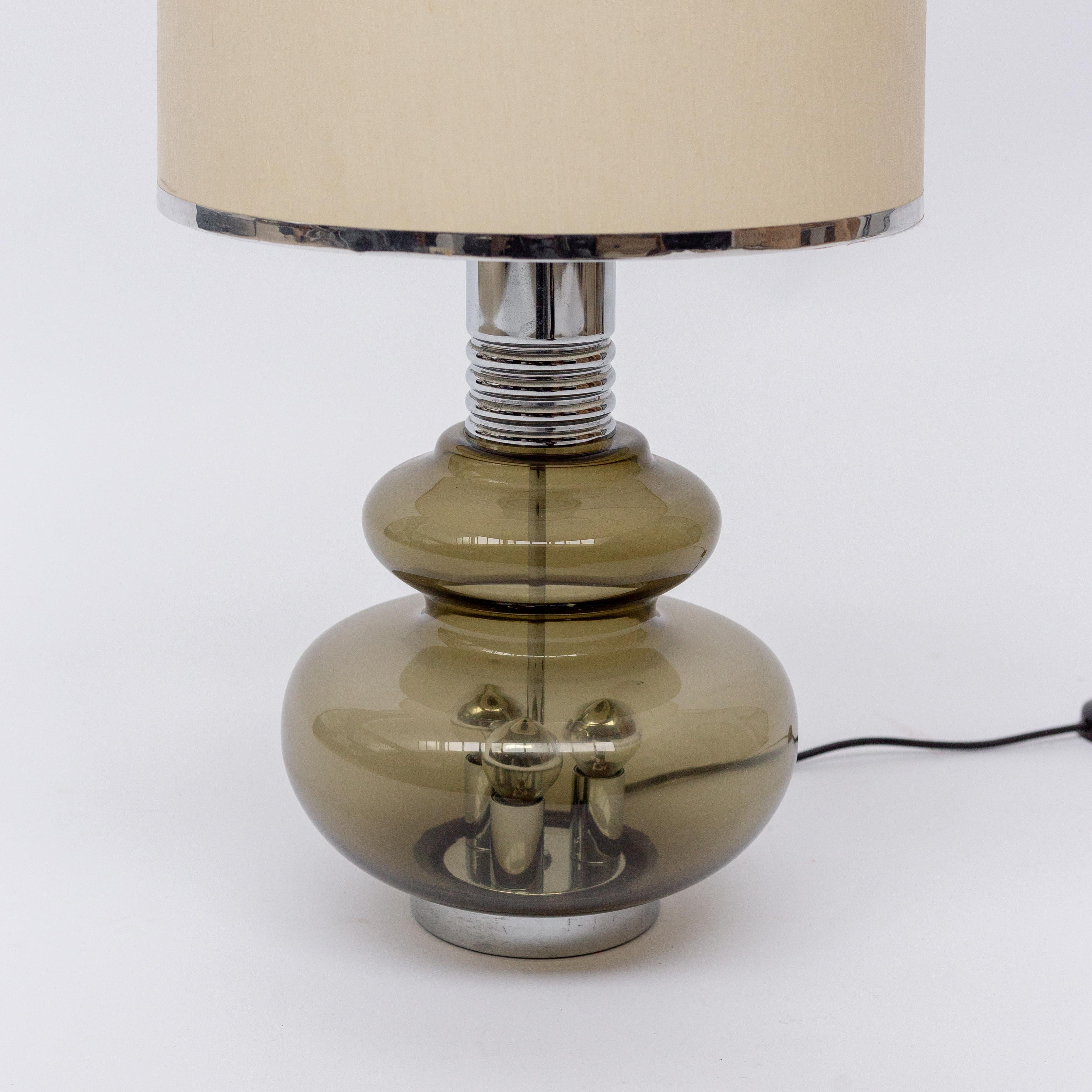 Table lamp manufactured by Doria Leuchten in Germany in the 1960s. Structure in smoked glass with chromed details. Three-light in the glass bottom and one light under the shade.
           