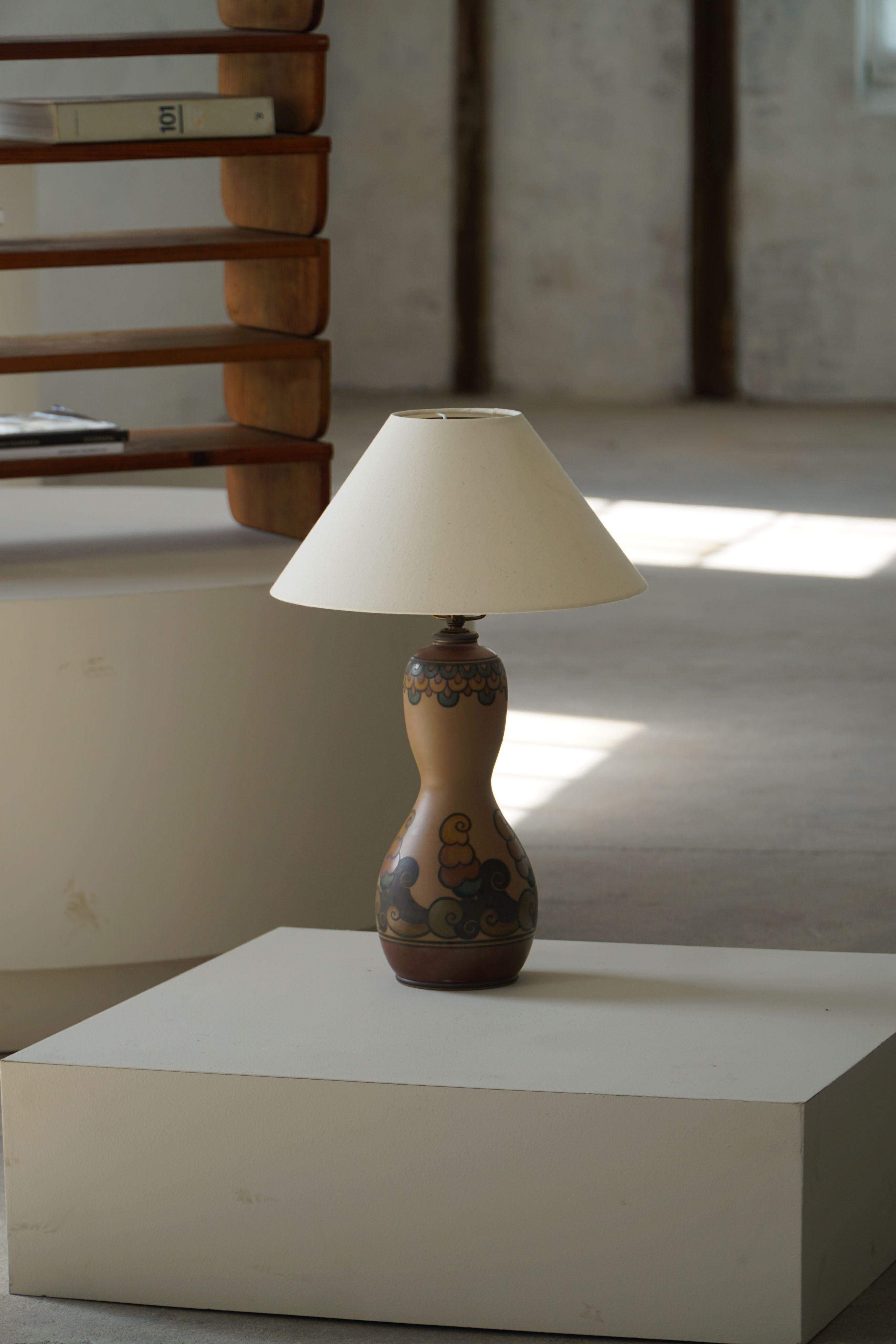 A finely hand-decorated terracotta table lamp from the esteemed L. Hjorth ceramic studio on the island of Bornholm, Denmark. Dating from the early 20th century, this piece exemplifies the refined craftsmanship and artistic vision for which Hjorth