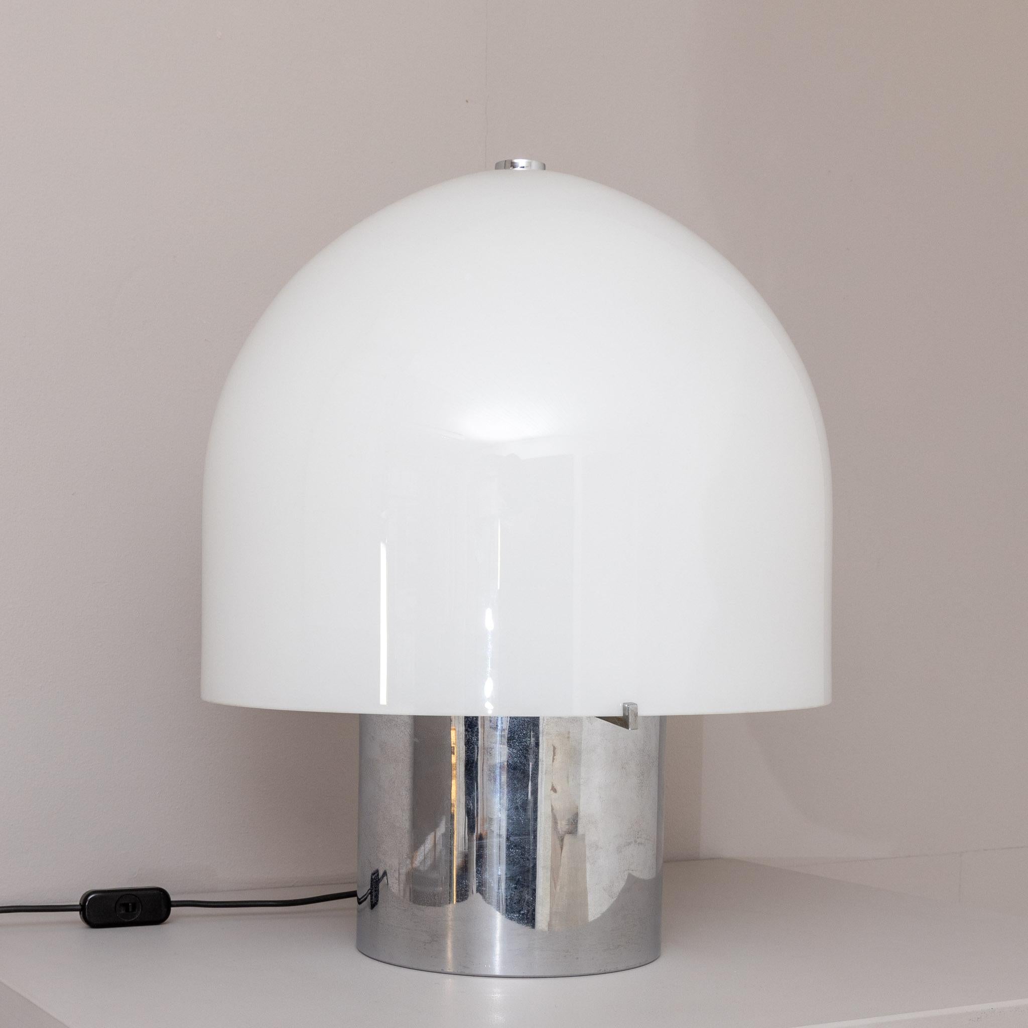 Large table lamp on cylindrical chrome base and white opaque acrylic lamp shade.