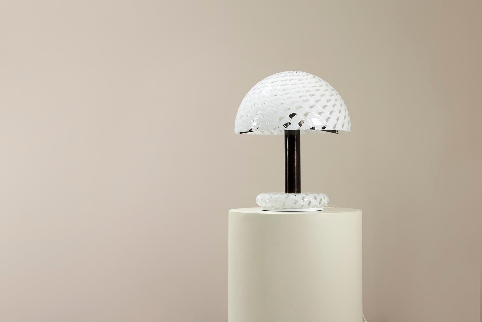 La lámpara de mesa de Carlo Nason modelo LT 354, diseñada en la década de 1960 y producida por AV Mazzega, ejemplifica el diseño moderno de mediados de siglo, mezclando líneas limpias con una artesanía de alta calidad. Nason, famoso por su dominio