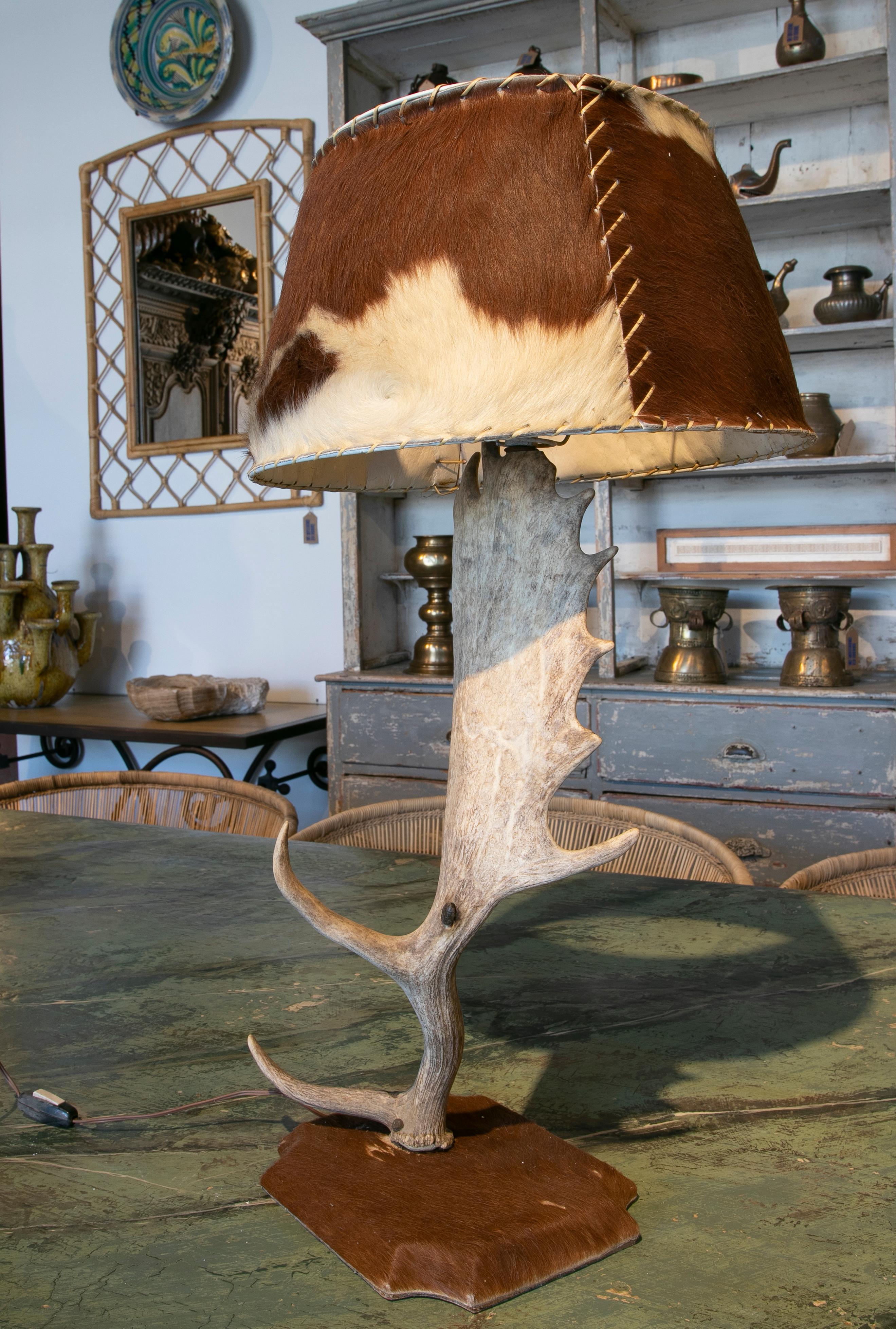 Table lamp made with an antler and deer leather used for the base and shade.