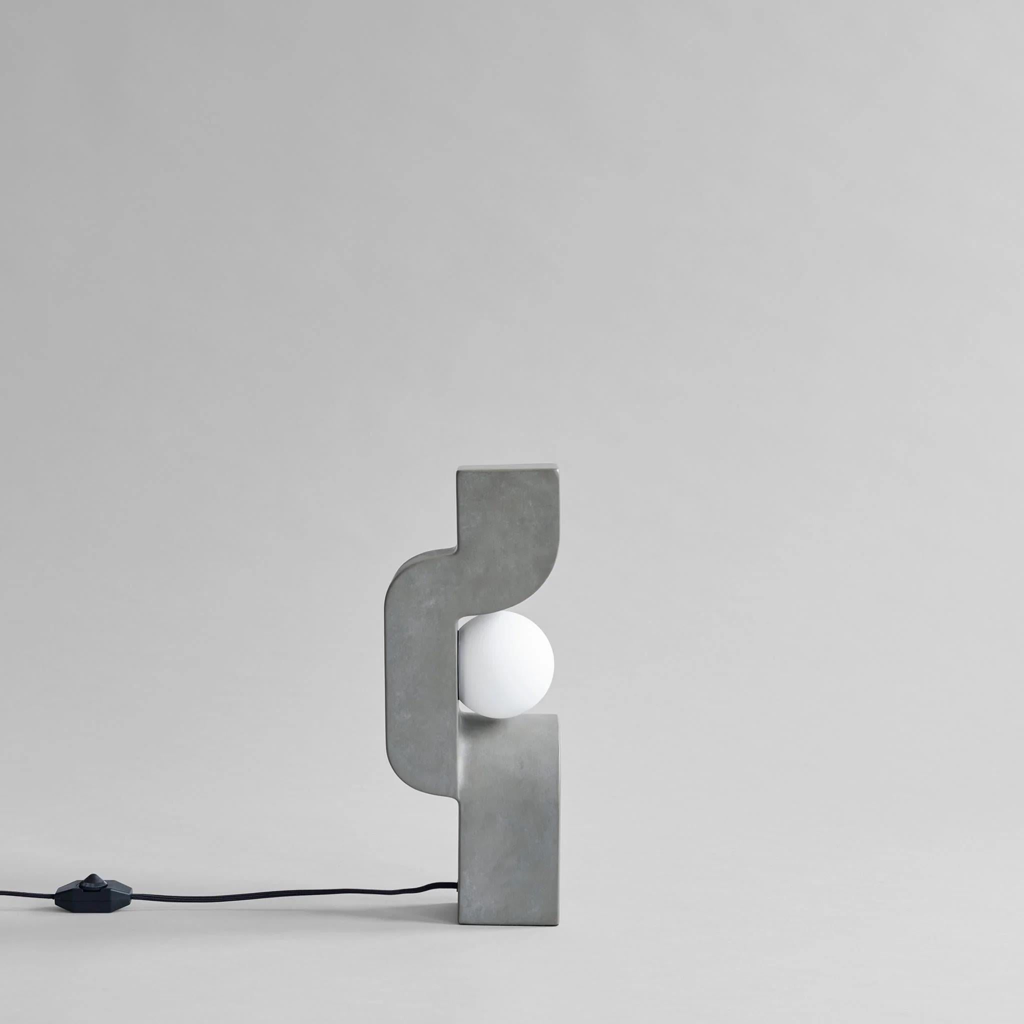 Lampe à poser, Mini modèle - Gris foncé, céramique, œuvre contemporaine.

Rappelant la silhouette d'un homme assis, cette lampe à poser est une sculpture lumineuse avec une sphère de verre éclairée positionnée au milieu d'une composition en spirale.