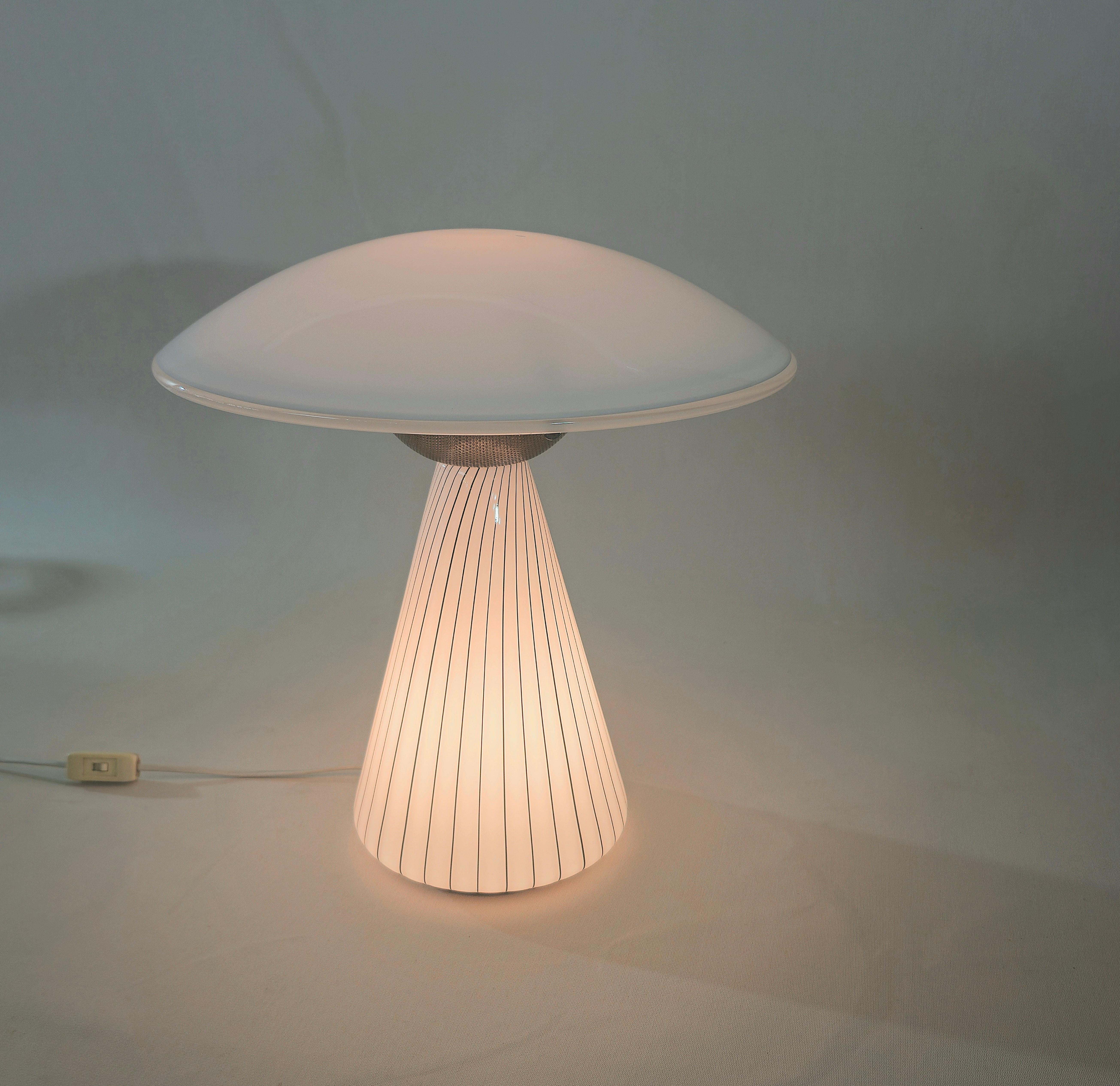 MICHELE DUSE Production Murano, Italie 1980 env. Lampe de table à deux lumières, corps en forme de champignon avec tige conique en verre de lait décoré de bandes verticales noires, diffuseur circulaire arrondi en verre de lait. Marque de production.