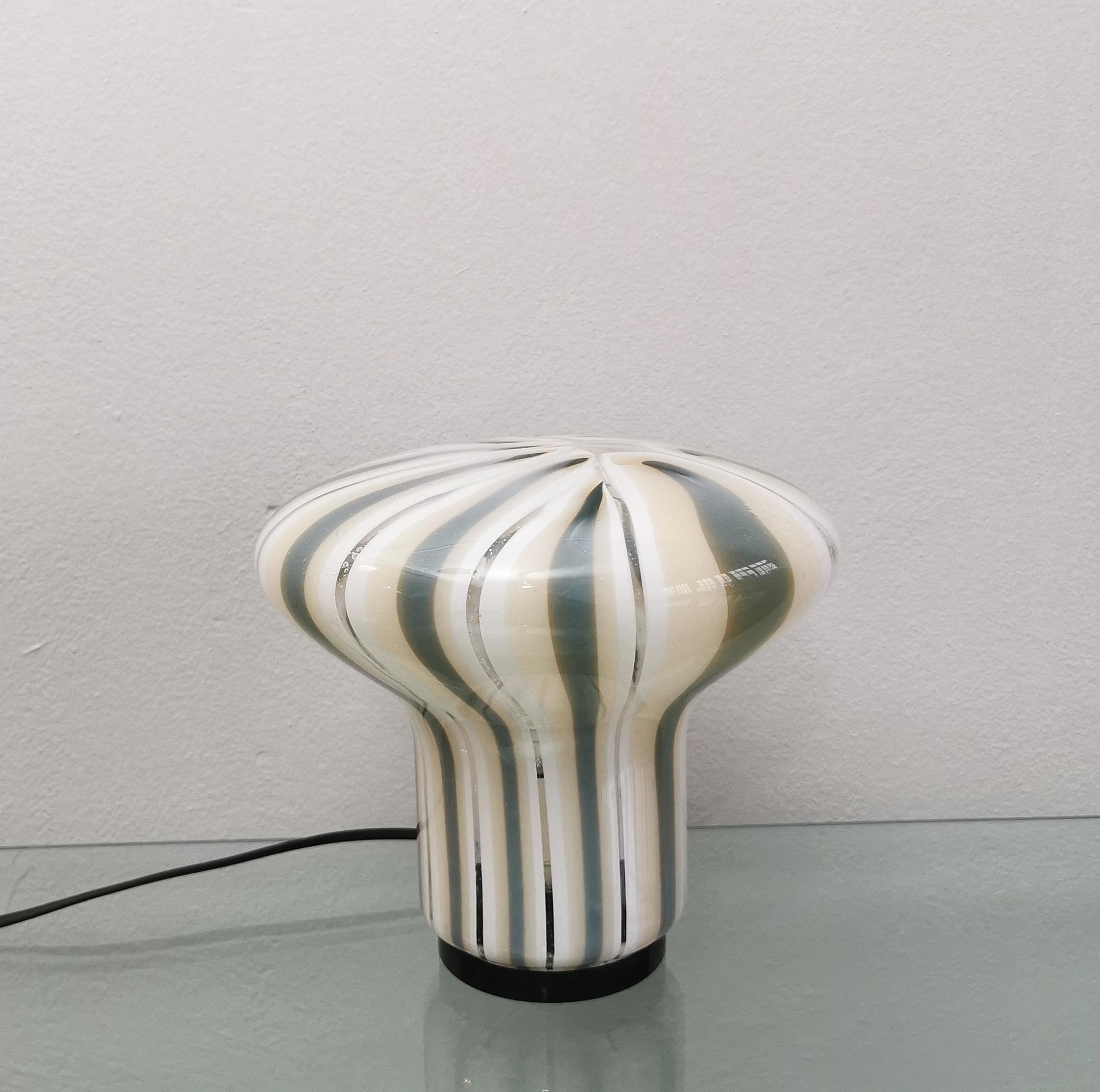 Particular table lamp with 1 light E27 produced in Italy in the 70s. The lamp has a nice shape, almost to represent a Murano glass mushroom with stripes in shades of gray, cream, white and transparent.