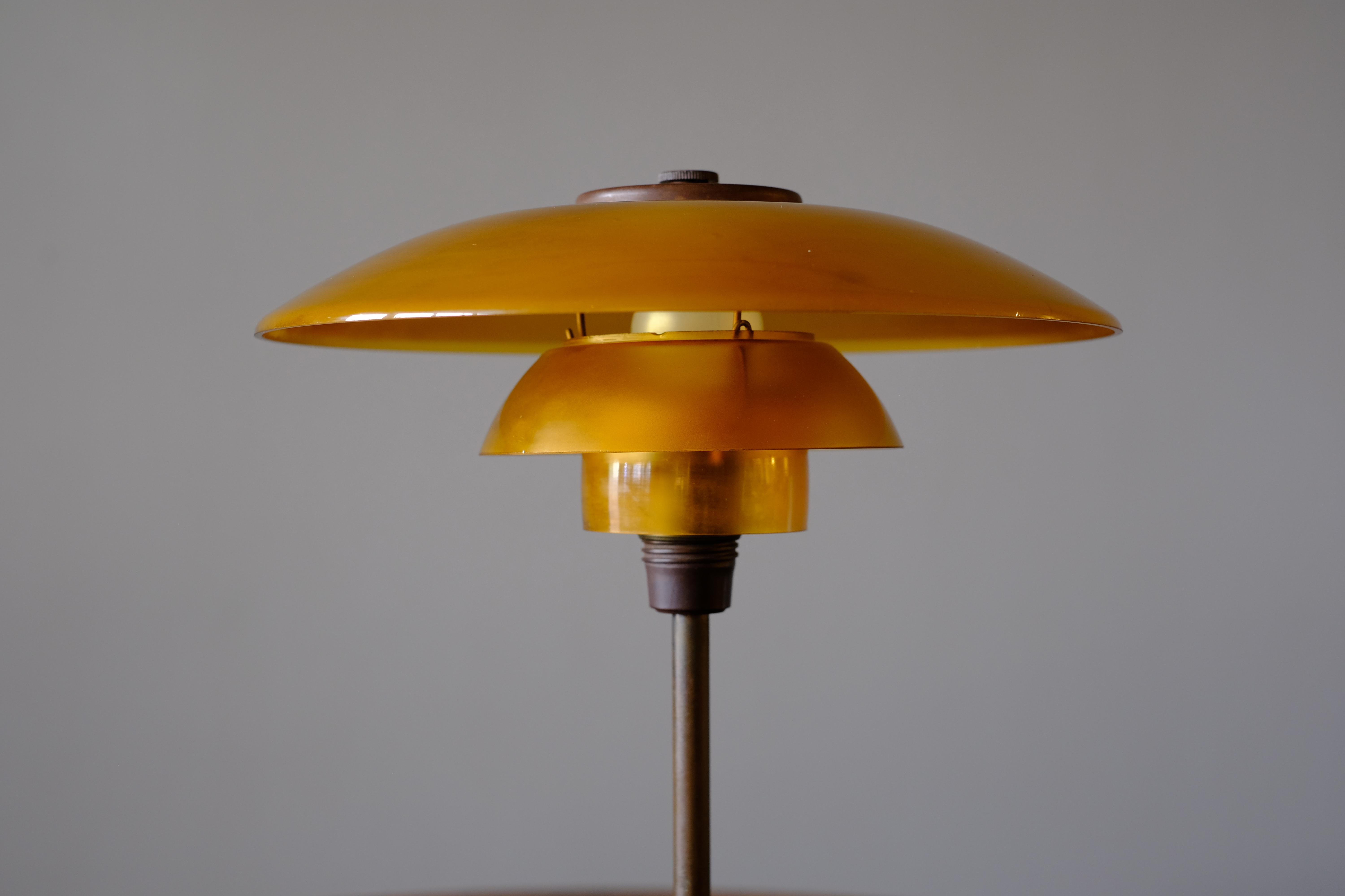 Beautiful early “PH3.5/2” table lamp by Poul Henningsen. It has a browned brass stem and a bakelite contact box with through switch. The shades are in lovely amber coloured glass. It was manufactured in the 1930s by Louis Poulson. As the typical