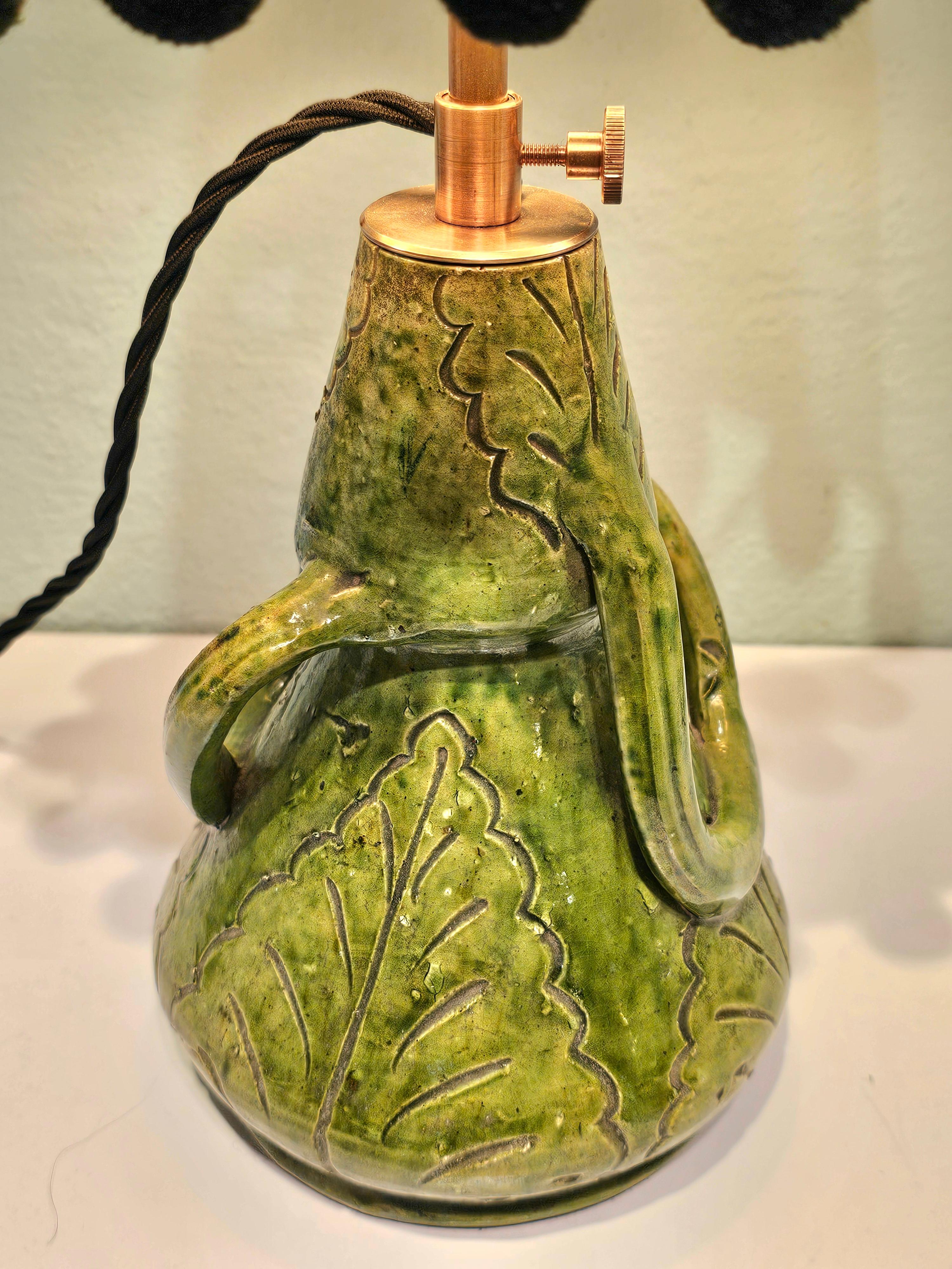 Petite lampe de table transformée à partir d'une poterie belge verte émaillée de Brendens Aardewerk.
Avec un abat-jour fait main en tissu avec pompon noir. Intérieur doré.
La hauteur est réglable