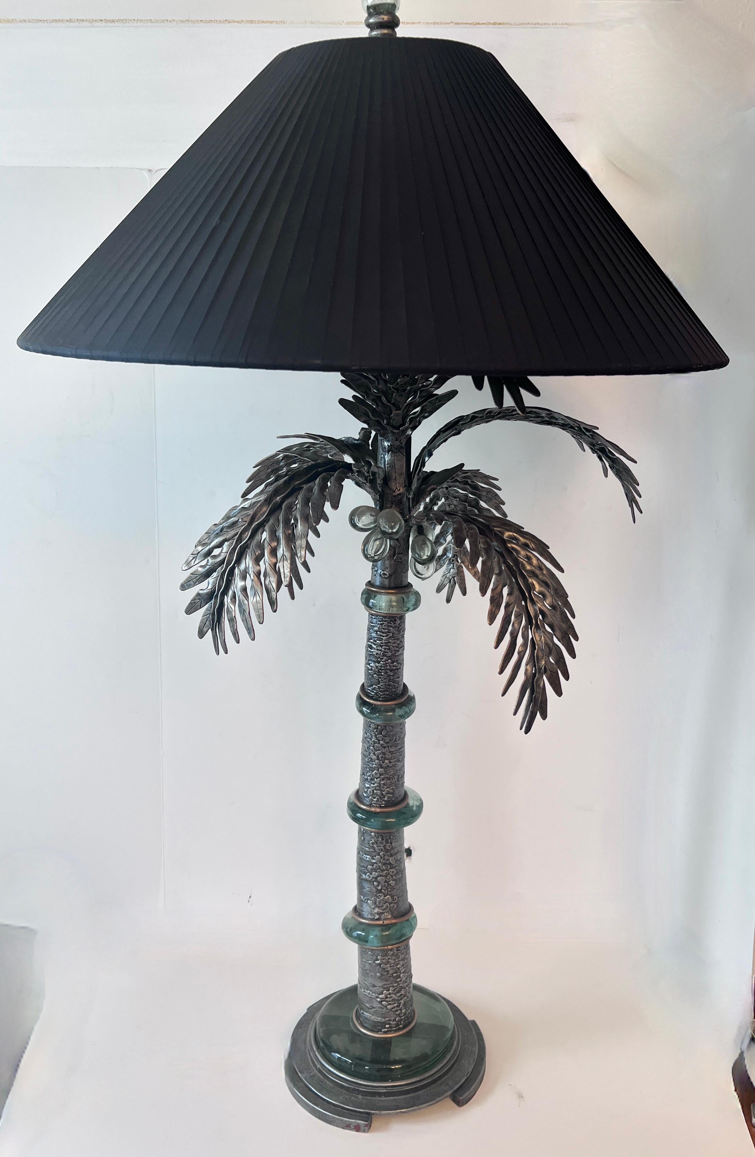 A beautifully designed and unique table lamp in the style and shape of a Palm Tree.

The lamp core is fabricated of metal with a glazed finish.  The curves in the palm are in segments separated by a thick cast green art glass - the top of the tree