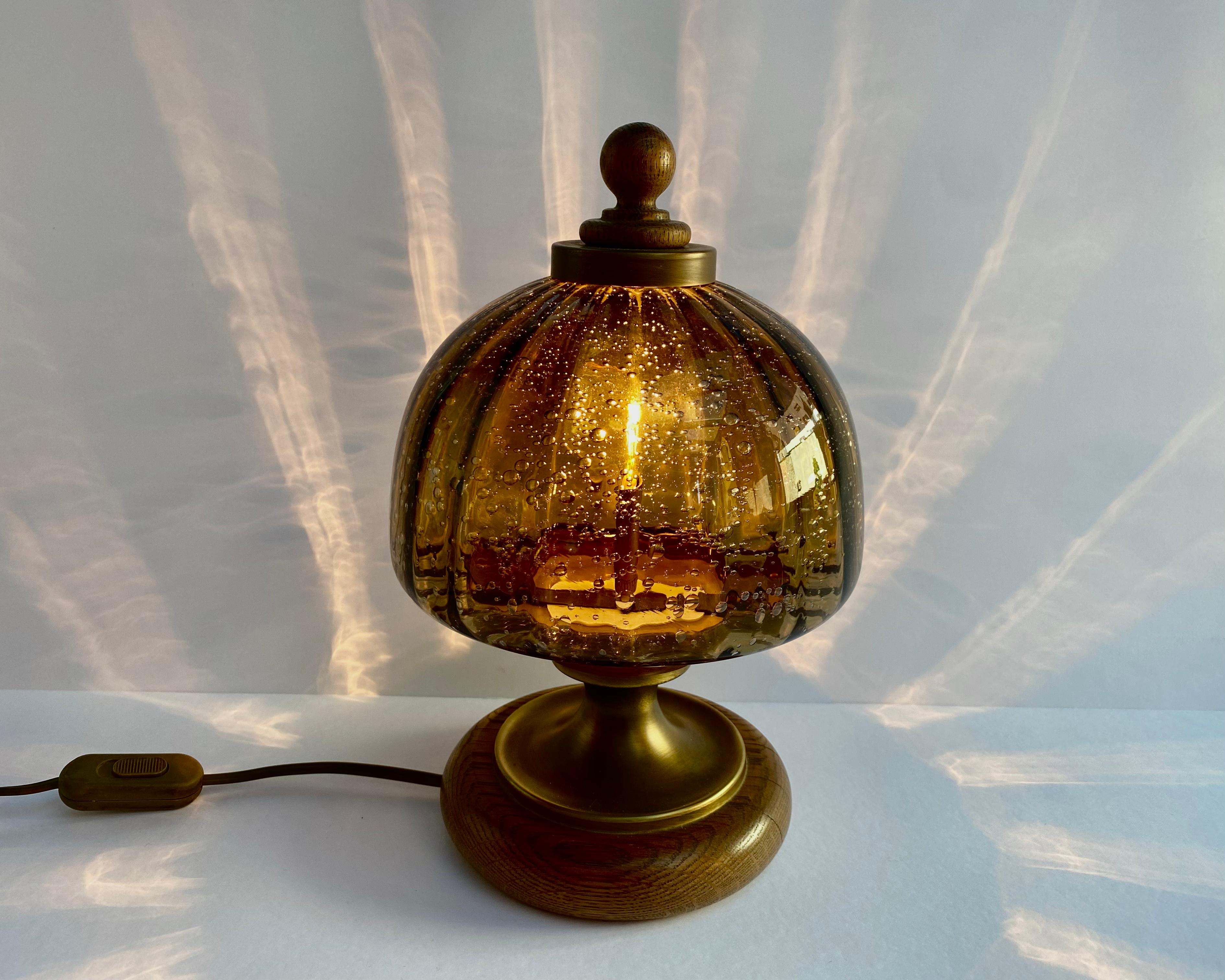 Well manufactured Art Deco style table lamp made from brass and wood installed with hand-blown art glass shade with bubbles.

Germany, 1970s.

The Table Lamp is ideal for traditional living spaces or for adding a cozy touch to any room. 

The right