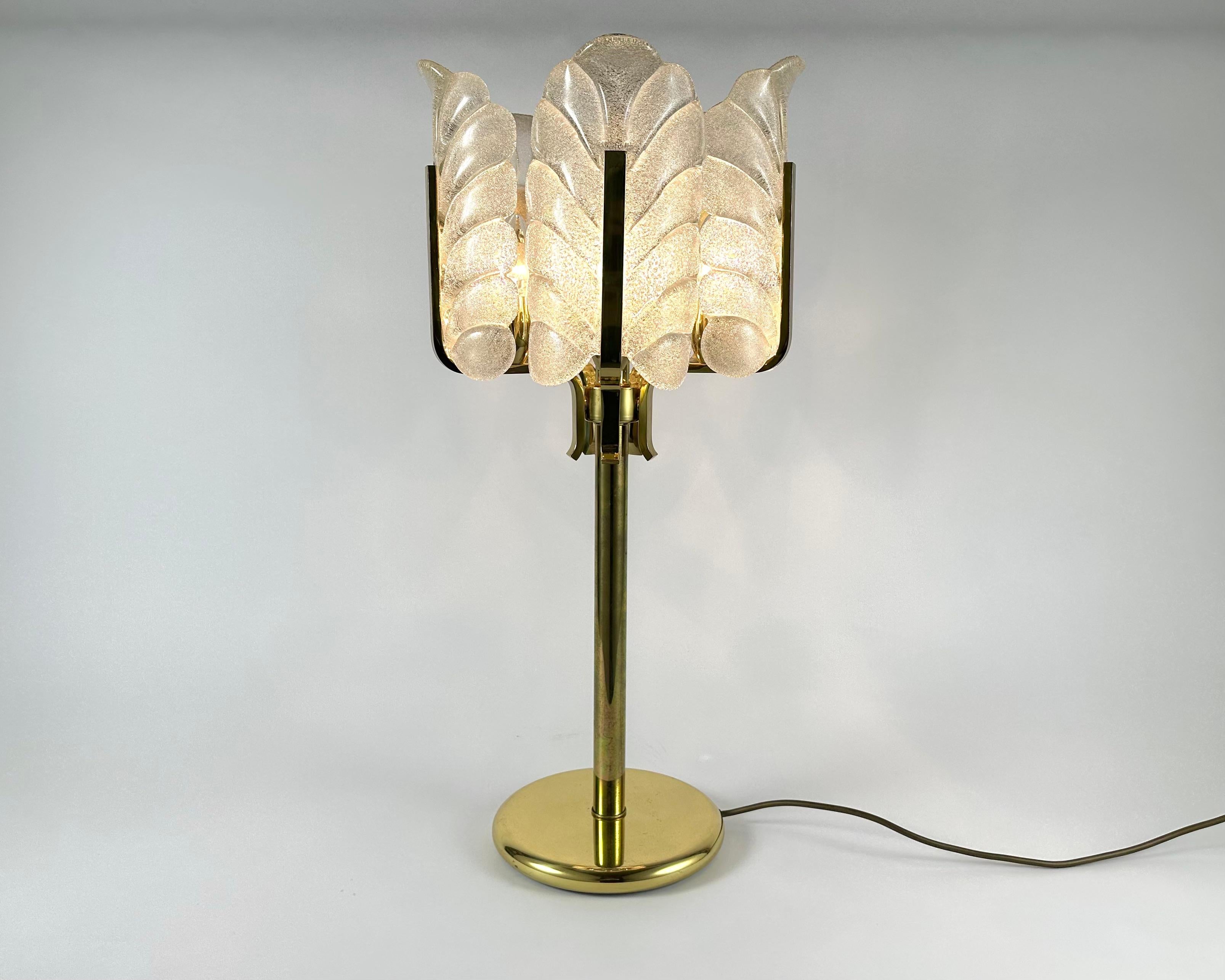 This sculptural Hollywood regency style table lamp was designed by Carl Fagerlund for the Swedish glasswork company Orrefors Lighting in the 1960s.

The lamp is made of shiny brass frame with five frosted and textured glass acanthus leaves which