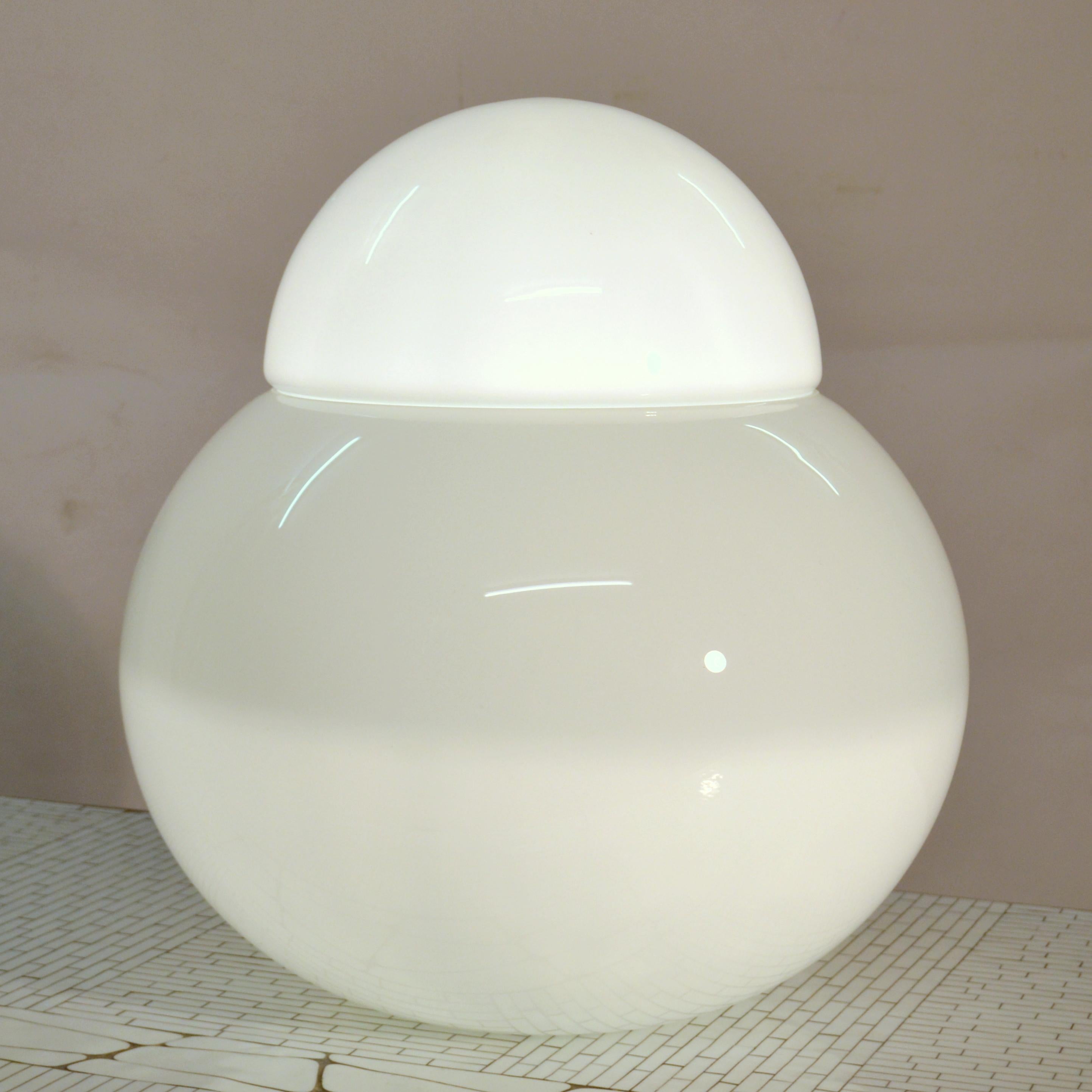Sculptural and minimal table or floor lamp Daruma in opaline white blown glass by Fontana Arte 1960s Italy. It is the largest size of six of this model, composed of two elements. Inside it holds one bulb which is easy to replace.
The table lamp