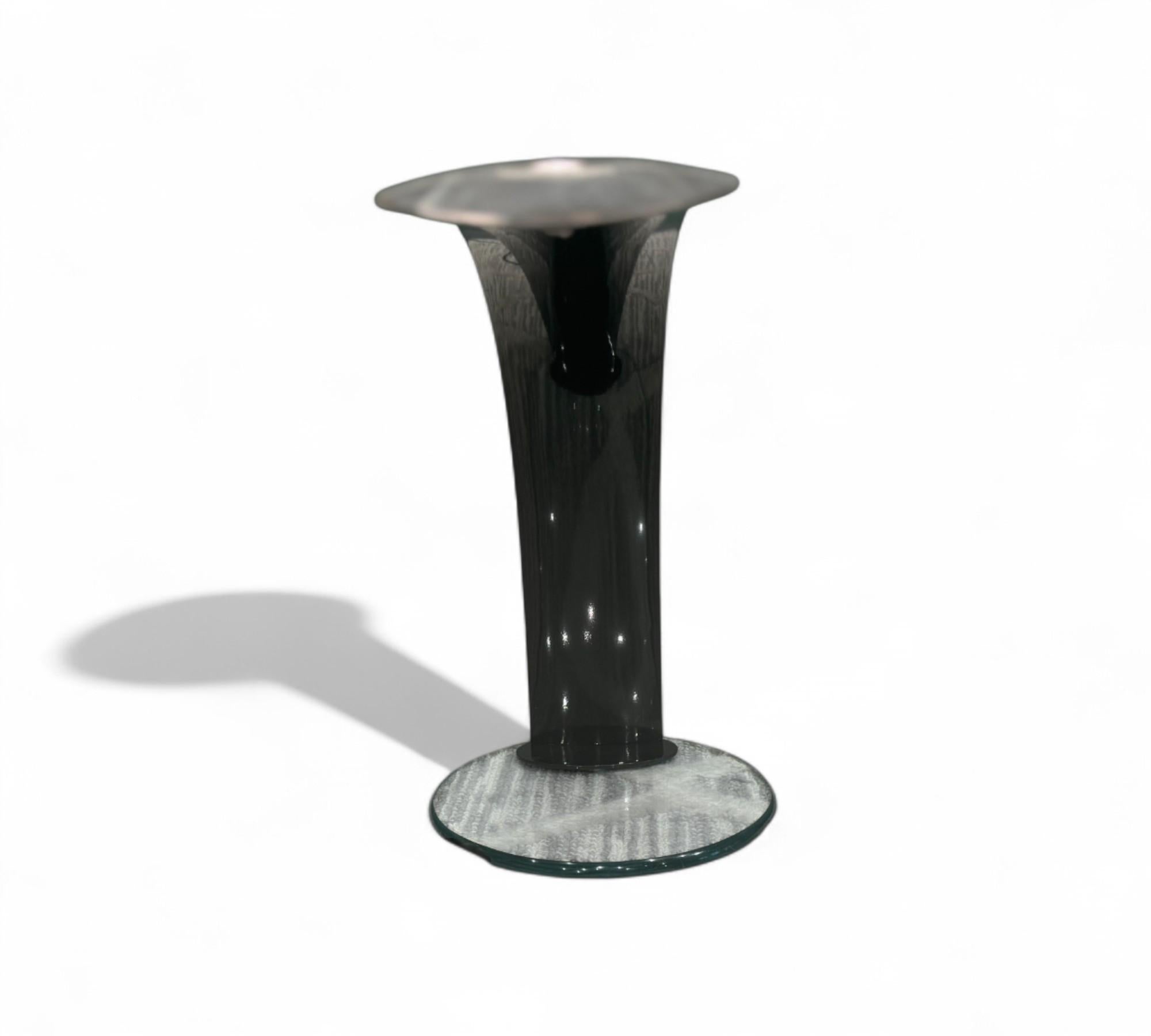 This modern desk lamp showcases a refined minimalist aesthetic, highlighted by its elegantly curved silhouette and glossy black finish. The lamp features a gracefully arched neck that extends from a sleek, circular glass base, providing both visual