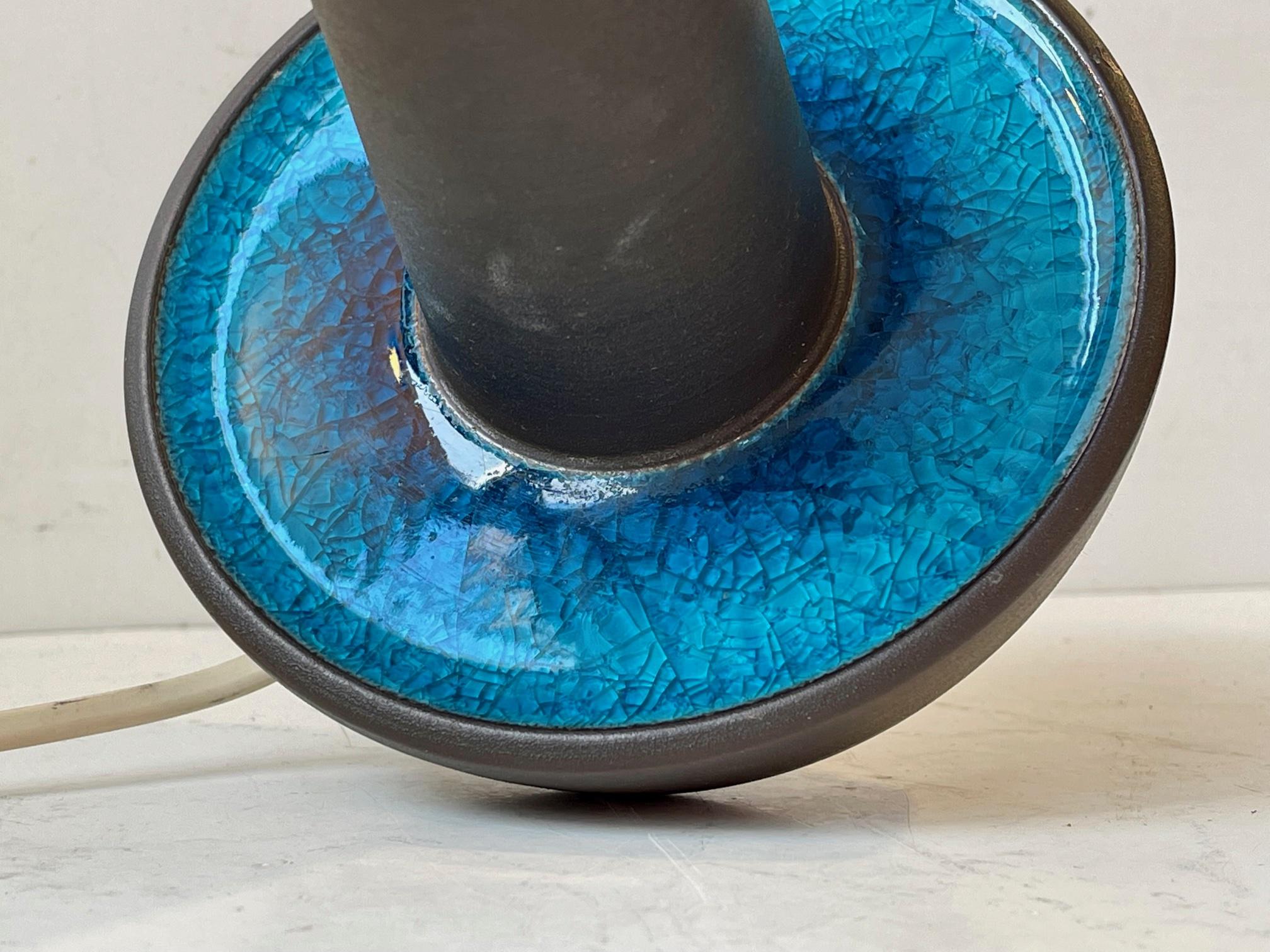 Eines der begehrtesten Designs des dänischen Keramikers Einar Johansen. Diese Version mit auffälliger türkisfarbener Craquelé-Glasur und blauen Akzenten wird gemeinhin als Caribbean Sea bezeichnet. Diese Leuchte hat die Nummer 1072 und misst 25 cm