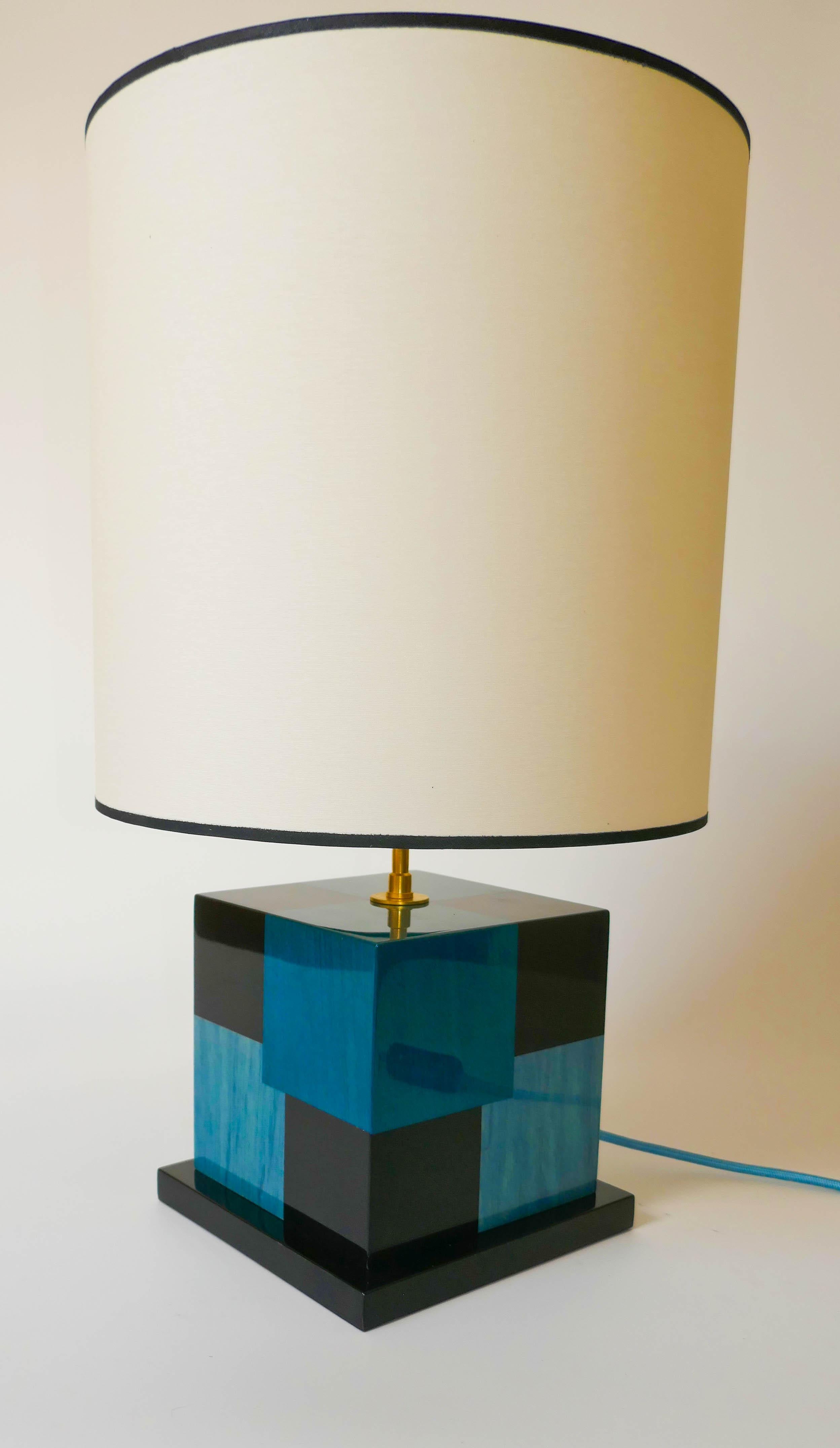Lampe de table en marqueterie de sycomore teinté noir, bleu clair et bleu foncé.
Fabriquée avec soin dans notre atelier parisien, cette lampe a un effet cinétique utilisant les différentes couleurs pour créer une impression de profondeur. La lampe