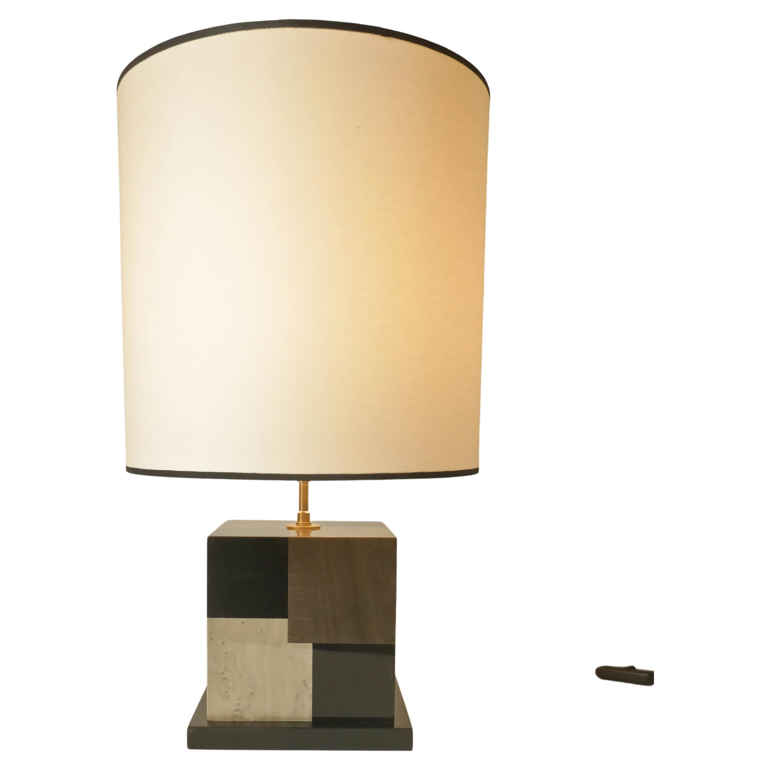 Table lamp in tinted black, light and dark Grey sycamore marquetry.
Carefully build in our Parisian workshop this lamp has a kinetic effect using the different colors to create an impression of deepness. The lamp is varnished. The bulb is a standard