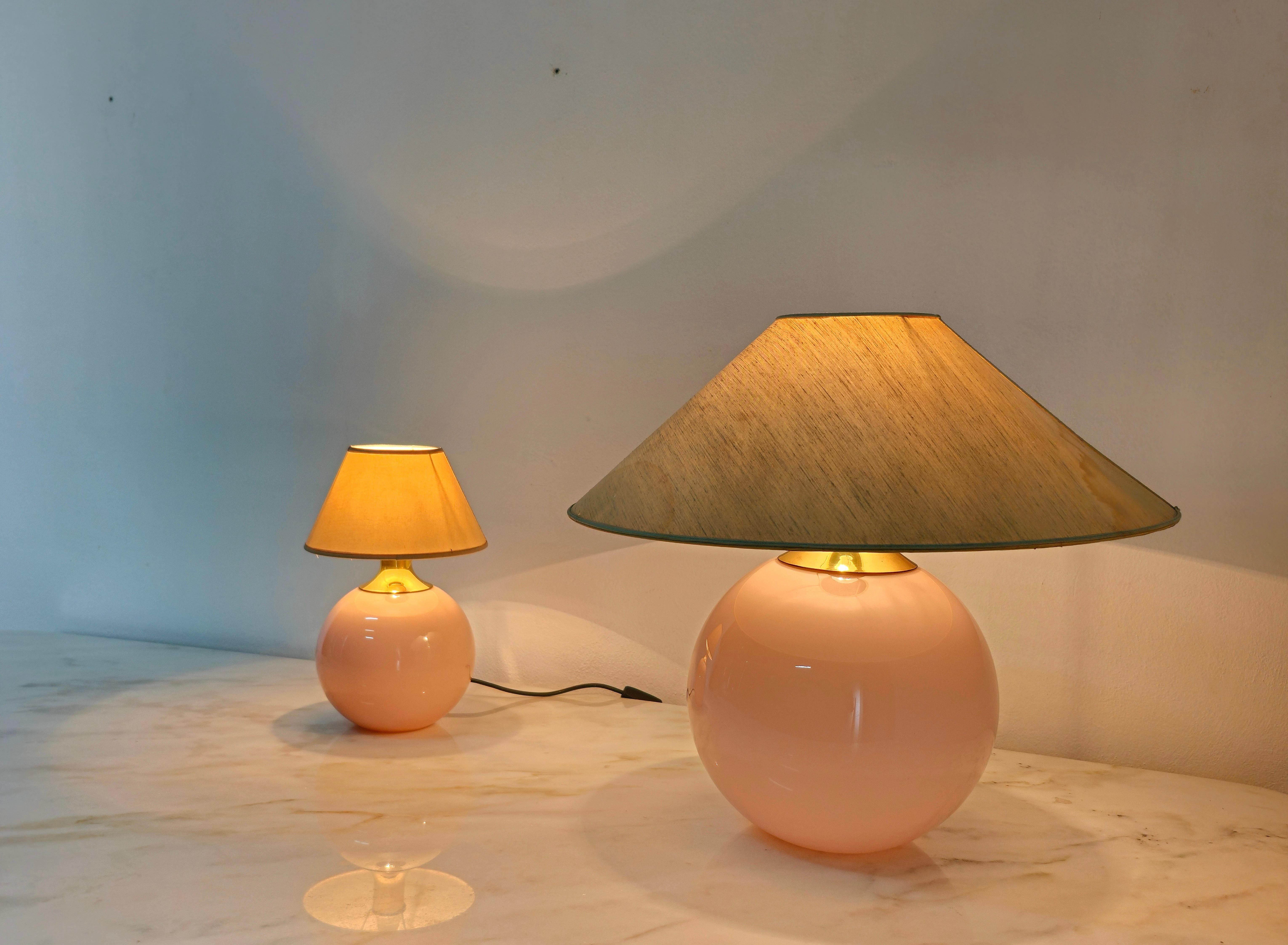 Set of 2 table lamps of different sizes Salina model produced in the 80s by the Italian glass factory VeArt. Each single lamp was made with a spherical Murano glass in shades of pink, a golden aluminum lamp holder accessory and a fabric