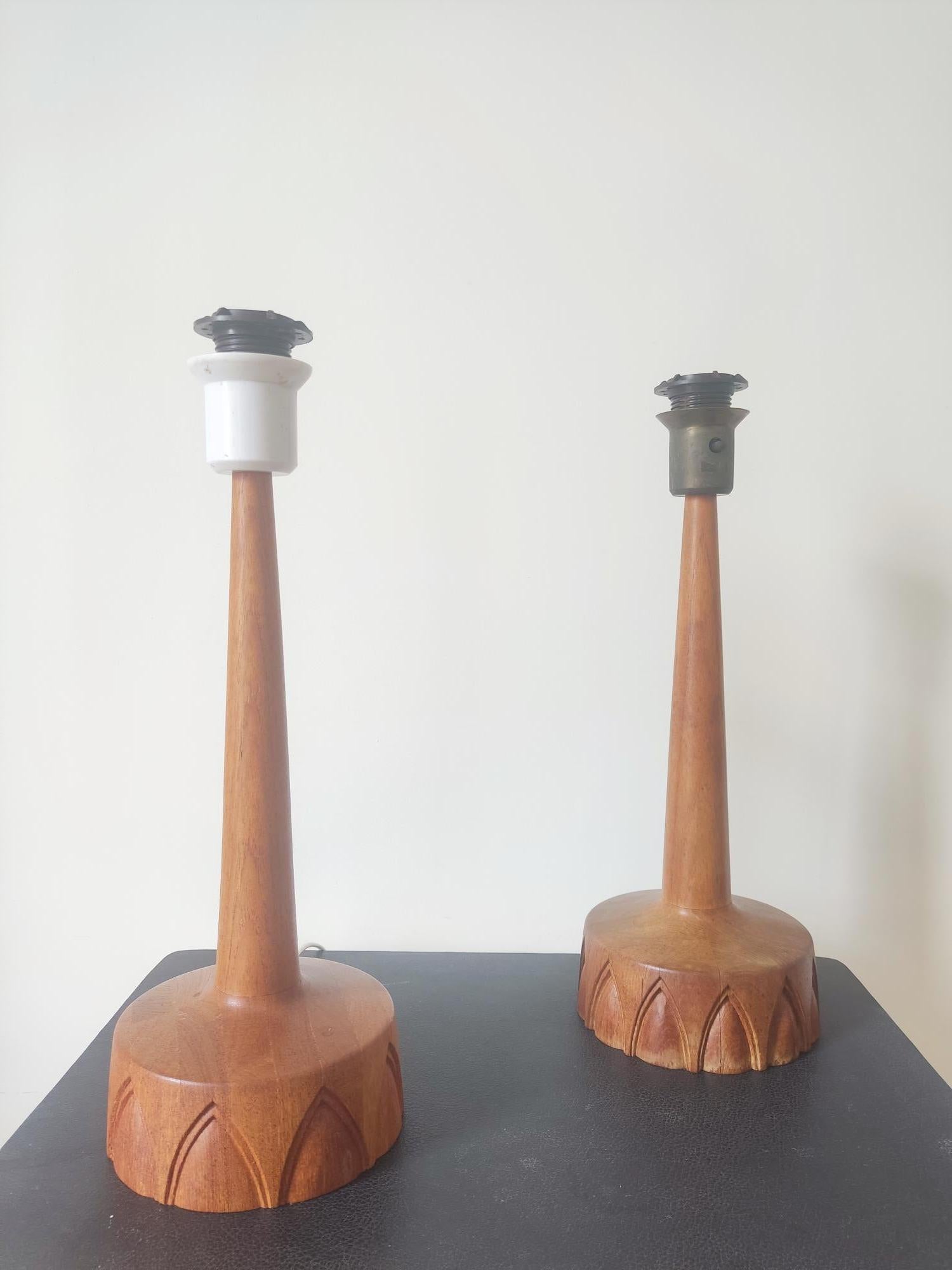 Cette élégante paire de lampes de table a été produite par AB Stilarmatur Tranås en Suède dans les années 1960. Fabriquées en bois de teck, les bases circulaires présentent un intéressant motif arqué sculpté à la main. L'interrupteur est un bouton