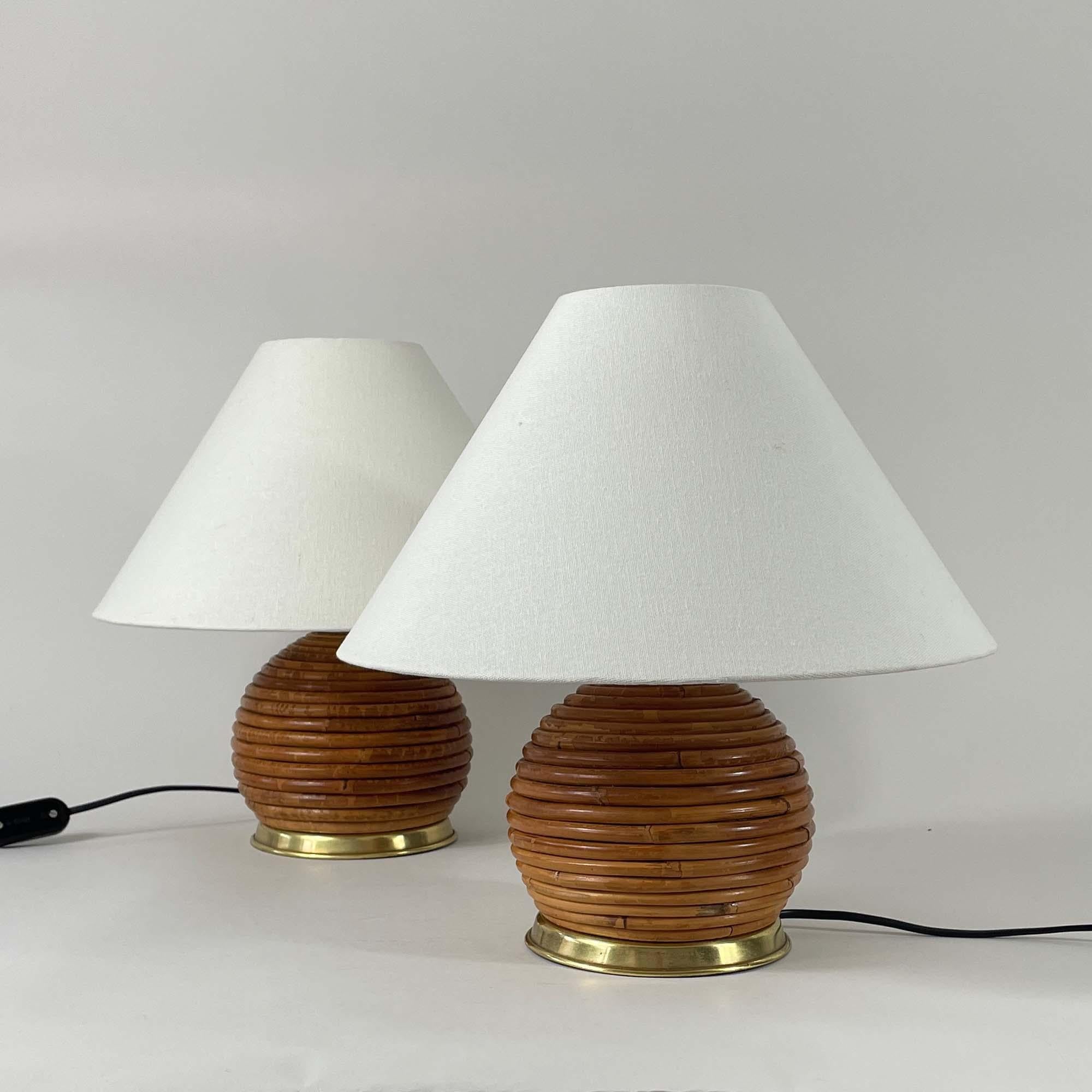These mid-century table lamps were designed and manufactured in Italy in the 1960s to 1970s.

The lights feature ball shaped bases crafted from pencil rattan, giving them a textured and organic appearance. The base has a brass accent ring at the