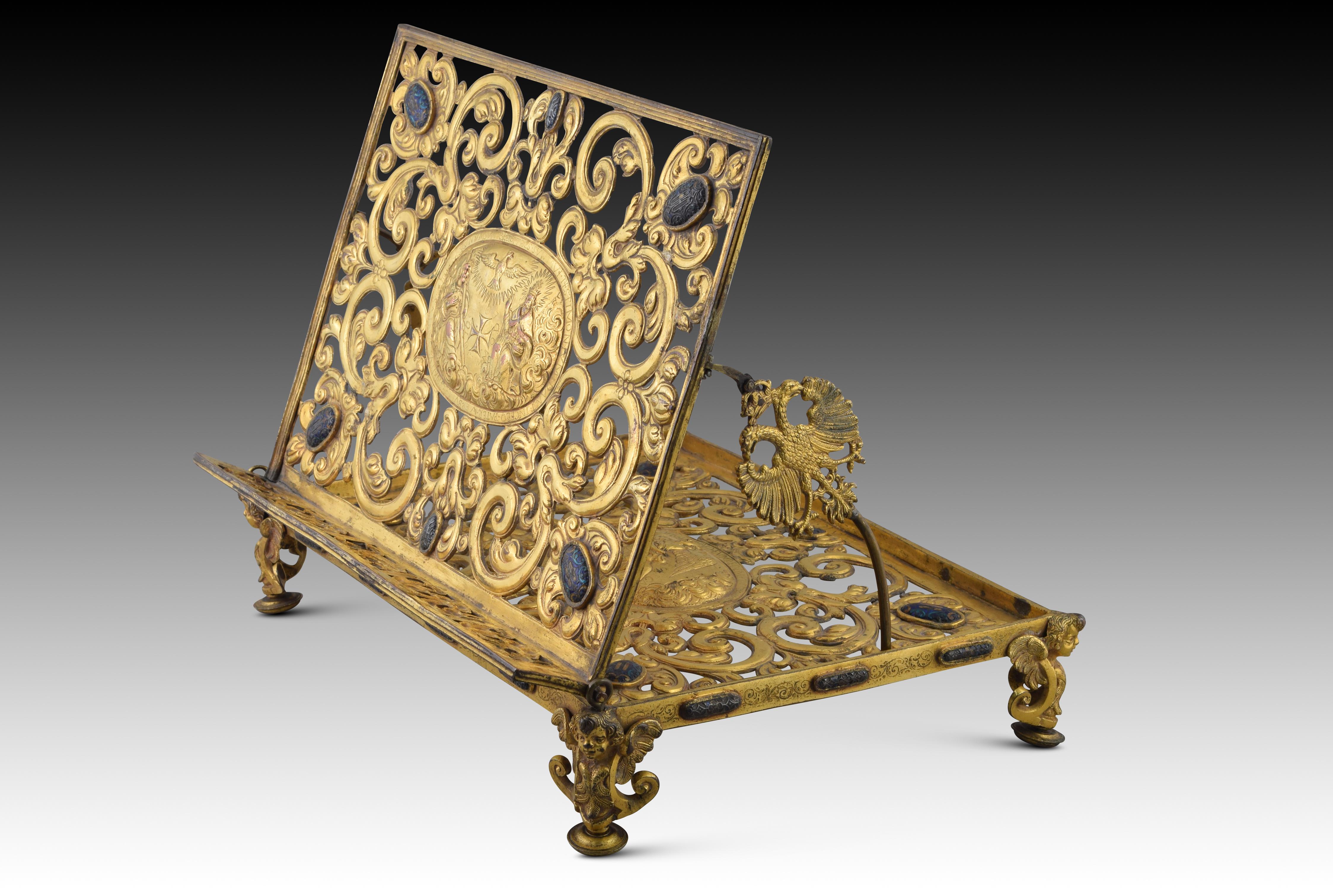Table lectern in gold-plated bronze. Enamel cabochons. Juan Ruiz, Madrid, 1656 
Rectangular portable tabletop lectern made of cast bronze relieved, cut out, chiselled, engraved and gilded and vdecorated, in addition, with colored enamels in ovals,