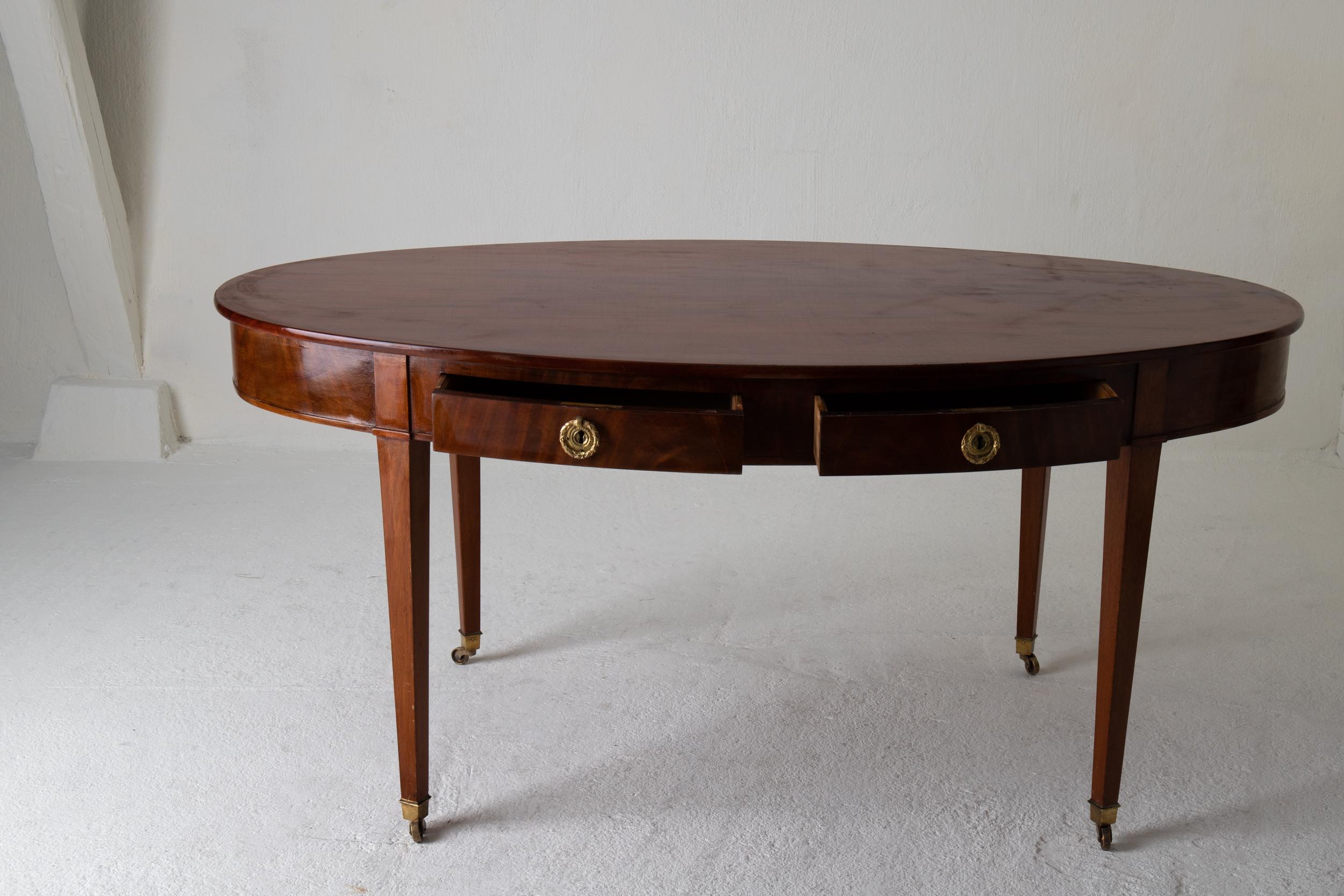 Table library Swedish mahogany Gustavian, Sweden. A stunning library table in an oval shape made during the early 19th century and Gustavian period in Sweden. 2 drawers on each side in the apron. Tapered legs ending in brass casters.

   