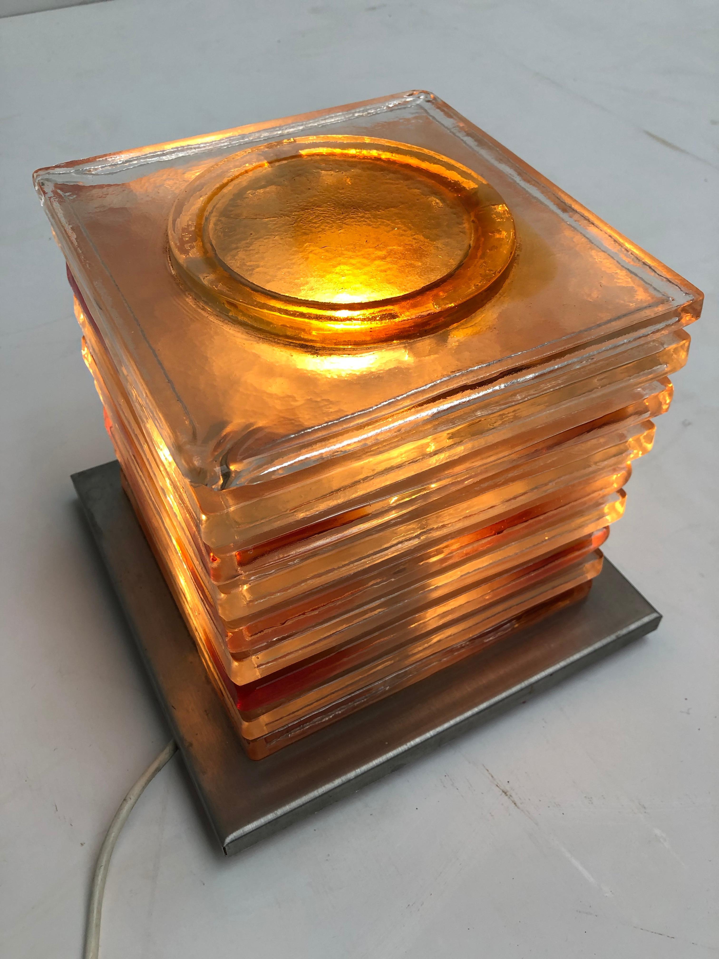 Lampe de table des années 1970 réalisée par Albano Poli (le fondateur de Poliarte) pour l'entreprise artisanale italienne de luminaires Poliarte.

Cette sculpture lumineuse italienne est composée de pièces de verre coloré carrées et empilées,