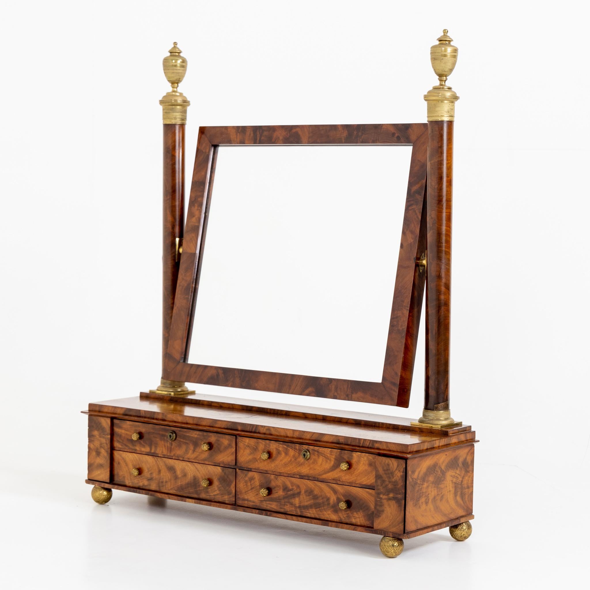 Table mirror in mahogany on oak with brass urn-shaped pinnacles and four drawers.