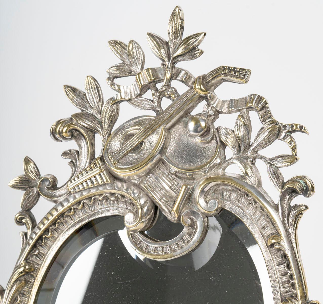 Table mirror in silvered bronze, 19th century, Napoleon III period.

A 19th century Napoleon III period silver plated bronze table mirror, decorated with musical instruments, bevelled mirror.
H: 40cm, W: 23cm, D: 2cm