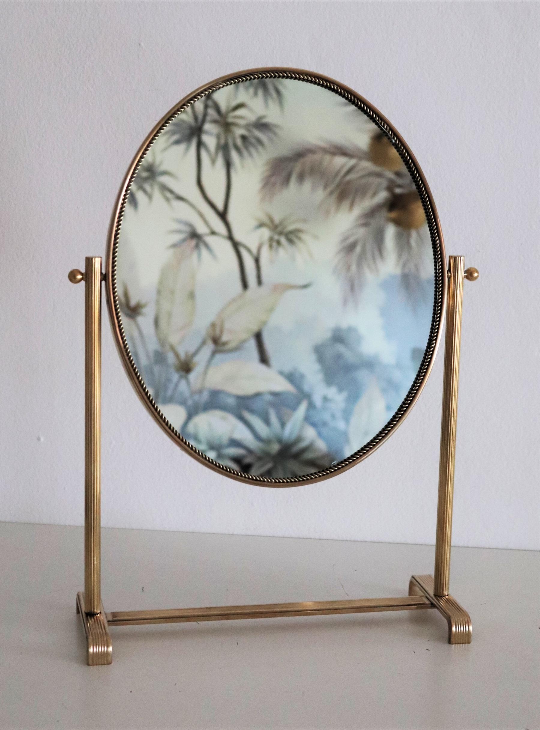 Gorgeous table or vanity mirror with full brass frame and base.
Made in Italy in the 1950s.
The round frame has decorative details also in brass.
The mirror can be turned around at 360° ; the backplate is made of dark wood.
The mirror glass is