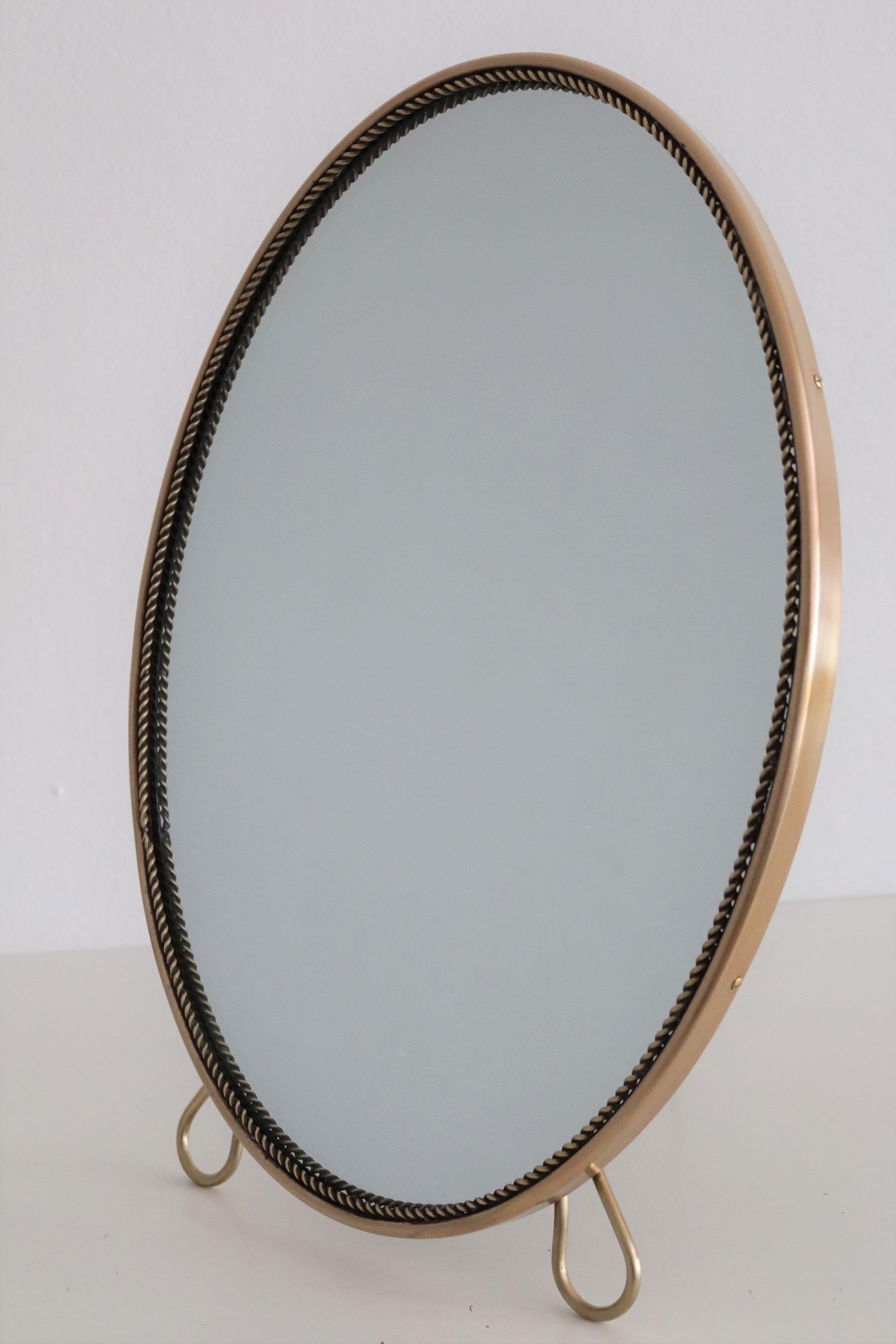 Gorgeous table or vanity mirror with full brass frame and stand.
Made in Italy in the 1950s.
The round frame has decorative details also in brass and the backplate is made of dark wood.
The mirror glass is new therefore in excellent condition.