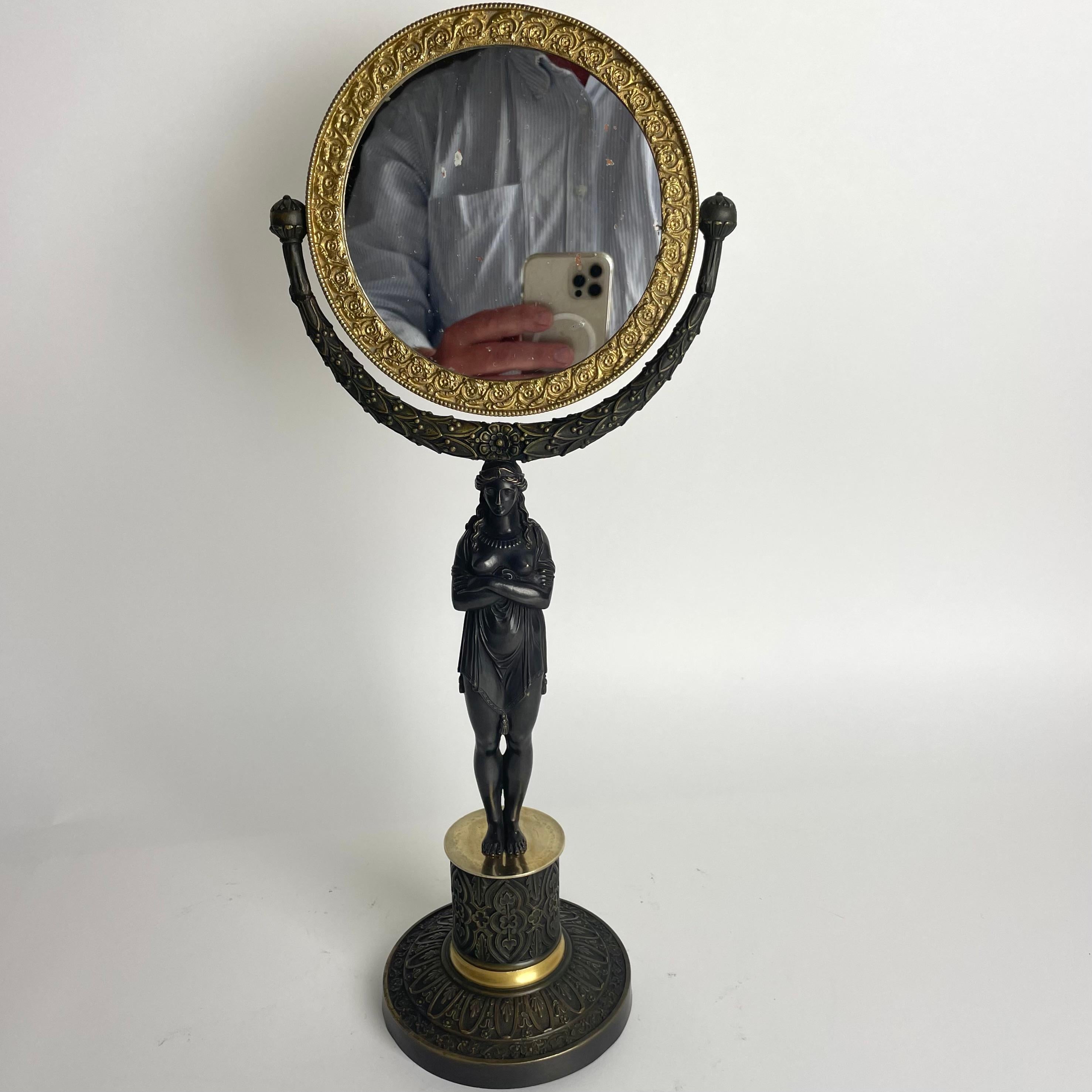 Très élégant miroir de table avec cariatide en Eleg français des années 1820 en  bronze doré et patiné foncé. 

Haute qualité de la fonte. Verre d'origine patiné. (Voir photos)

Usure correspondant à l'âge et à l'usage. 