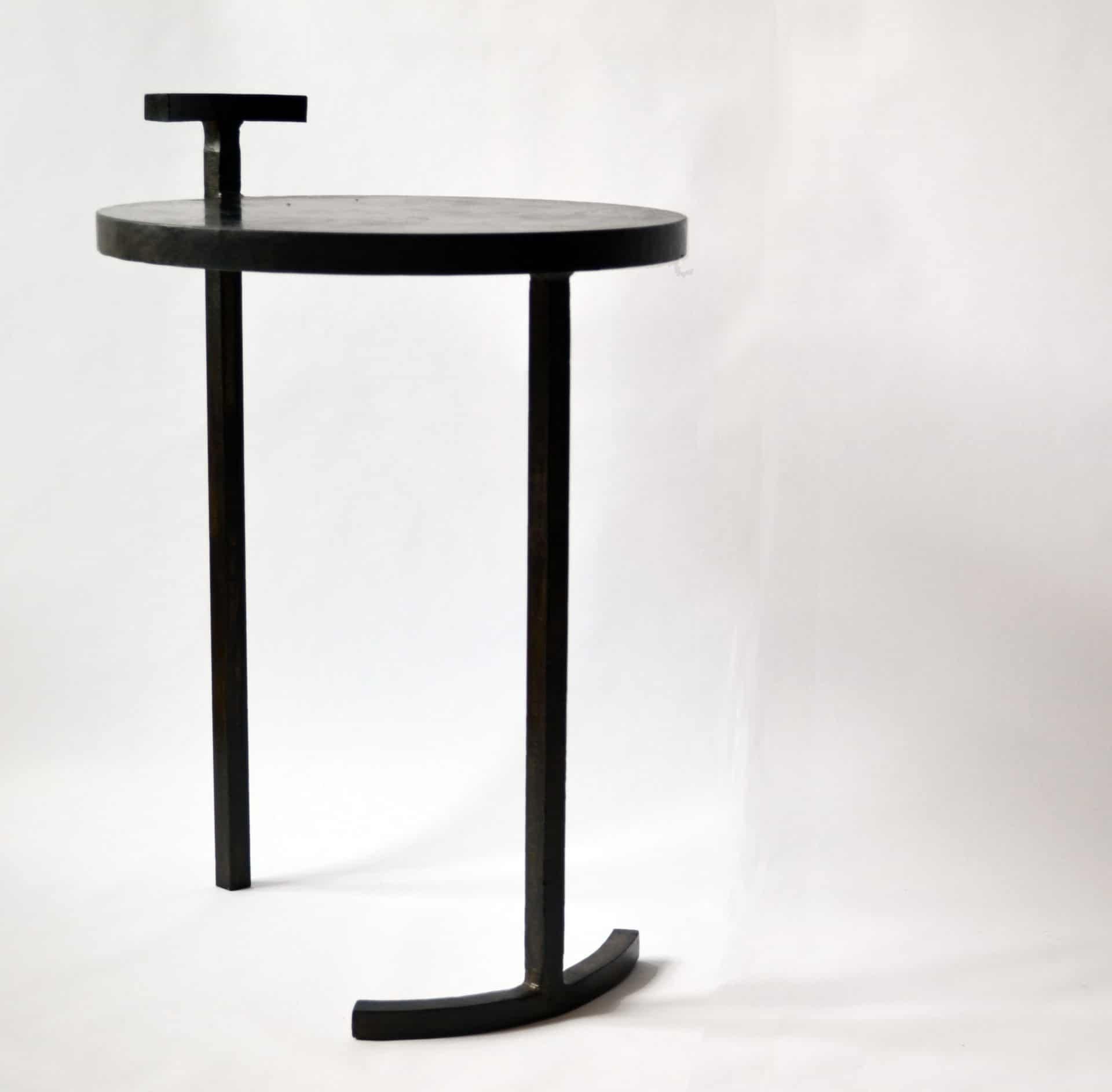 A striking design. This side table has only two legs.

This side table is made from cast blackened and waxed steel. A uniquely designed frame allows a 1 inch thick, cast steel, circular top to balance on two legs. This is the first table designed