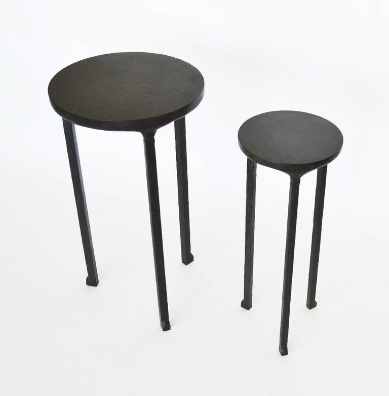 A set of two cocktail tables hand-carved from steel and finished with a blackened patina and wax. 

The small size makes this table set perfect for unique configurations or small spaces.

Table No 1: 12” diameter x 23” high
Table No 2: 8