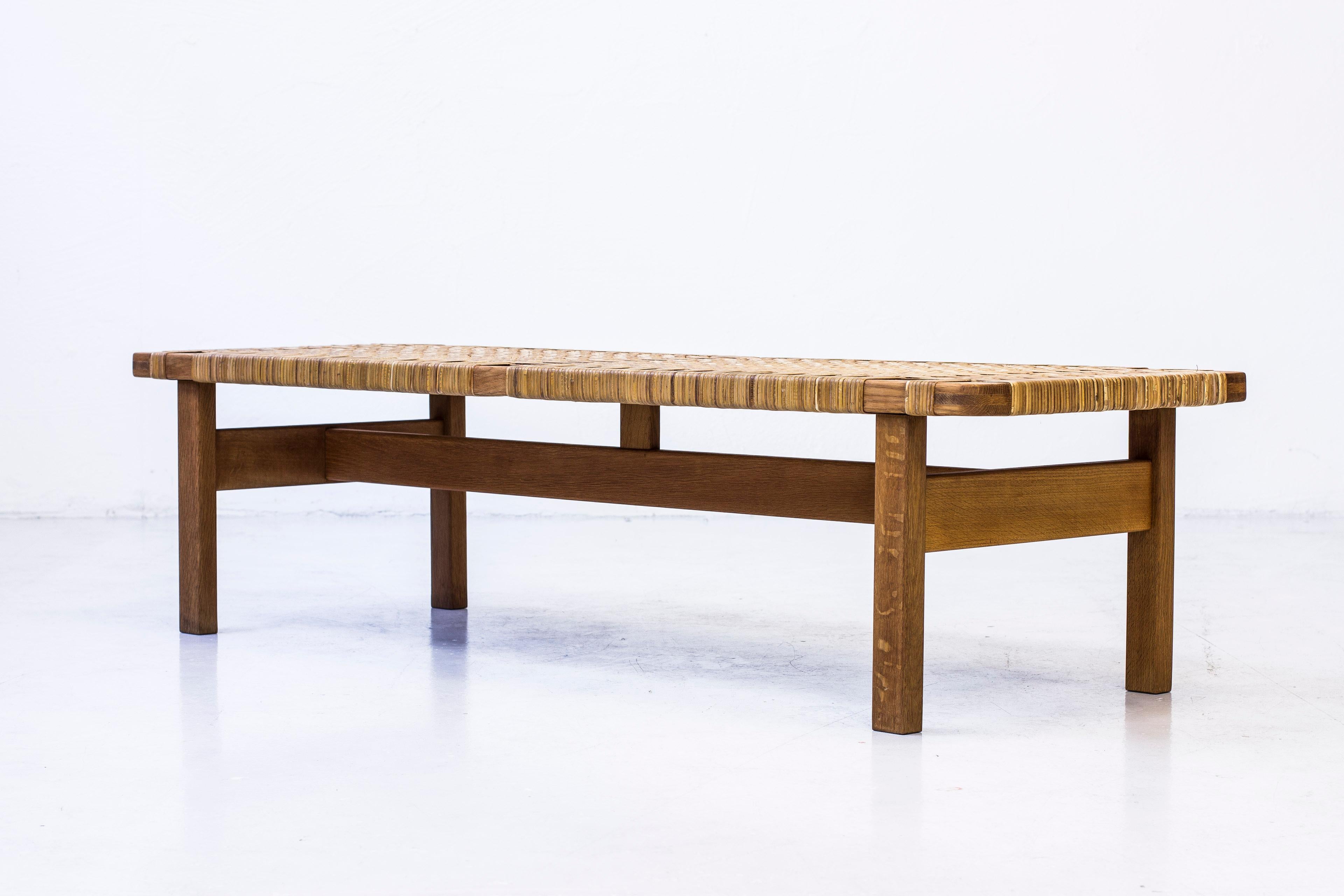 Bench or sofa/side table designed by Børge Mogensen. Produced in Denmark by Fredericia furniture during the 1950s. Made from solid oak with woven cane as tabletop or sitting surface. Excellent condition with light age related wear and patina.
 