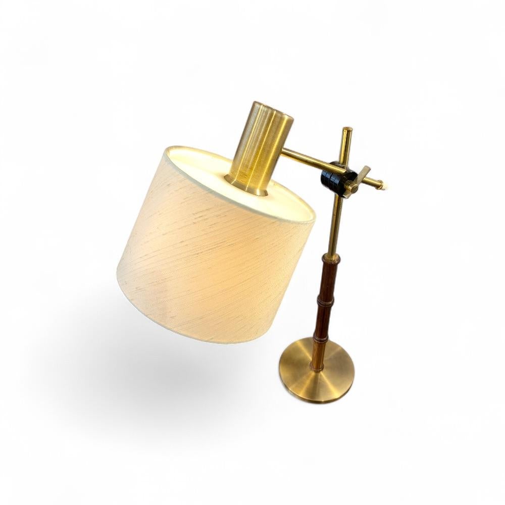Table or desk lamp by Falkenbergs Belysning, embodies the elegance and craftsmanship of Swedish lighting design. Its walnut stem, featuring a bamboo-like pattern alternating with brass sections, adds a touch of warmth and sophistication. A beautiful