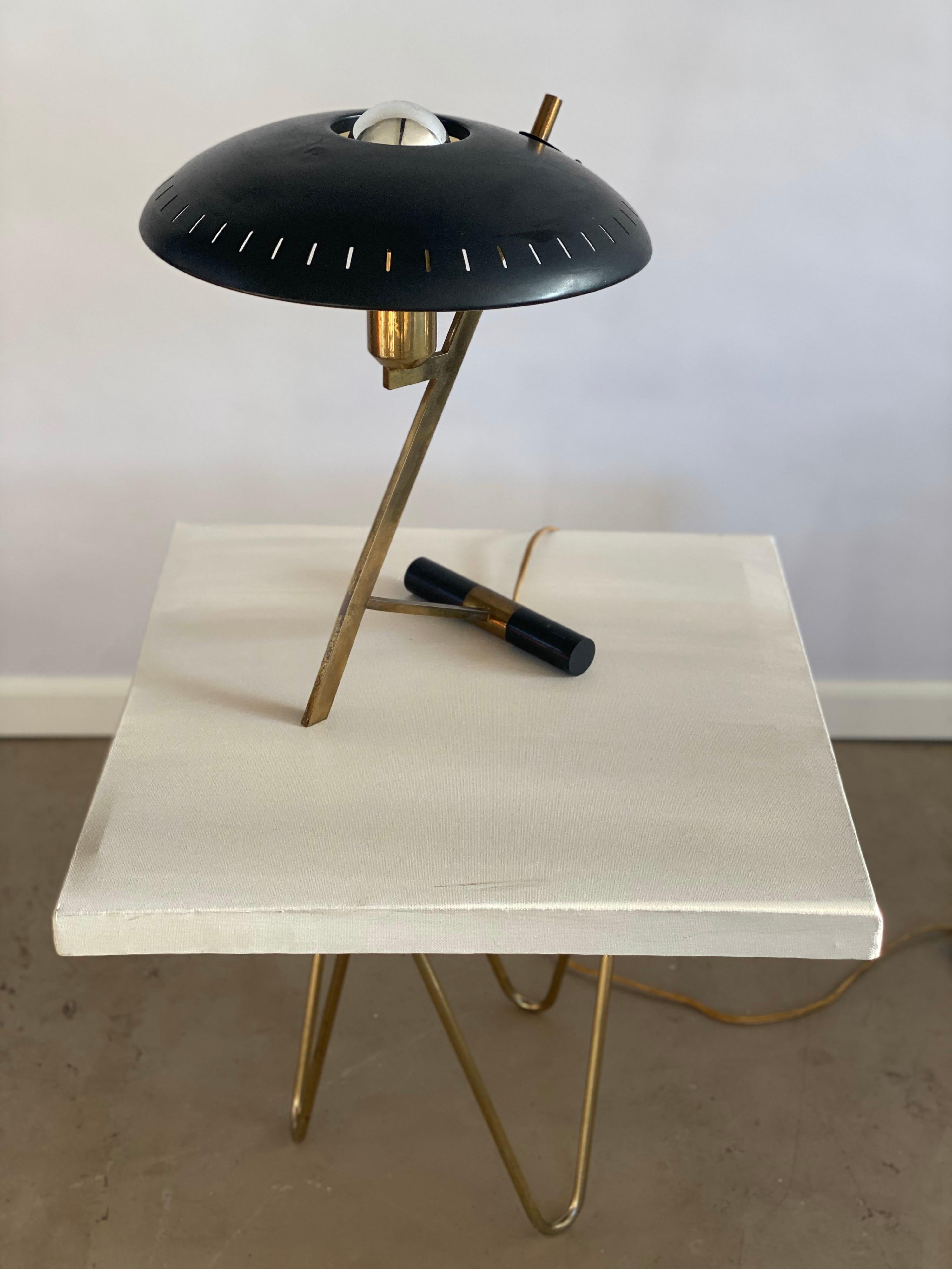 Two identical available. Beautiful iconic design by Louis Kalff for the renowned Dutch firm Philips, mid-1950s. This is the first edition with a brass frame and the black disk-shaped perforated black lacquered shade. The shade is the miniature of