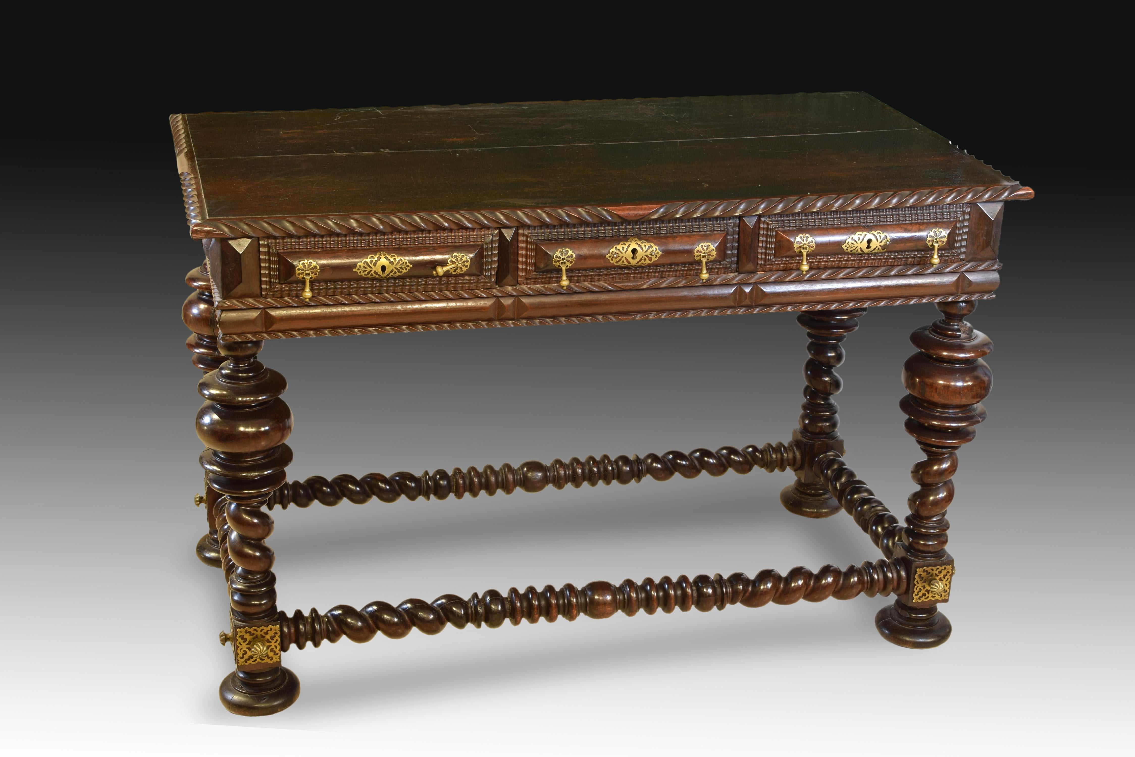 Table. Rosewood wood. Portuguese school, 18th and 19th centuries. 
 Rectangular carved wooden table with three front drawers with lock escutcheons and gold metal handles, which has four turned legs with thick discs and solomonic areas, joined