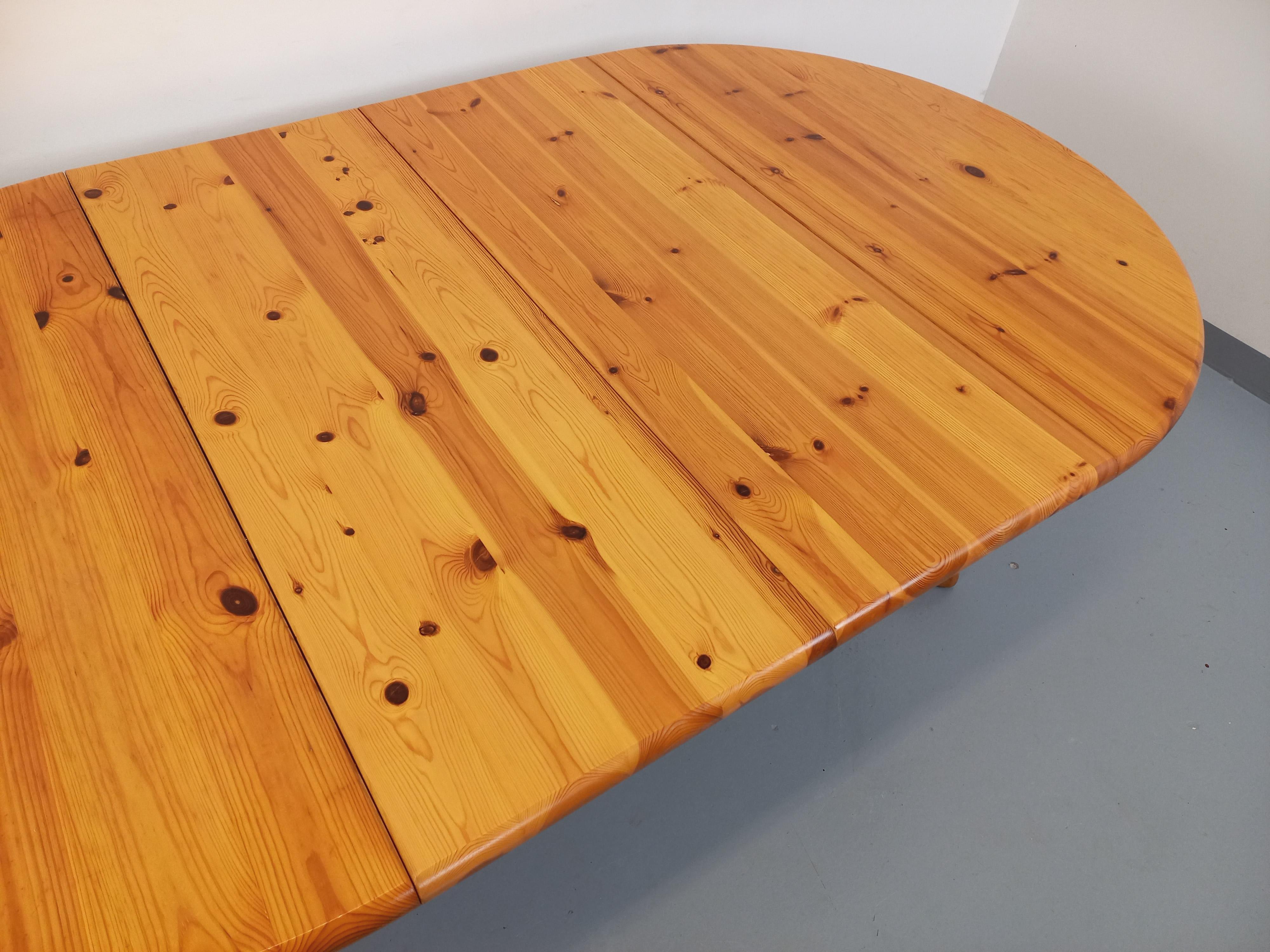 Table ronde vintage des années 60 70, en pin, dans le goût du designer danois Rainer Daumiller, pied central à 4 branches s'ouvrant en 2 pour laisser la place à une ou deux rallonges centrales non intégrées. Très bon état général avec quelques