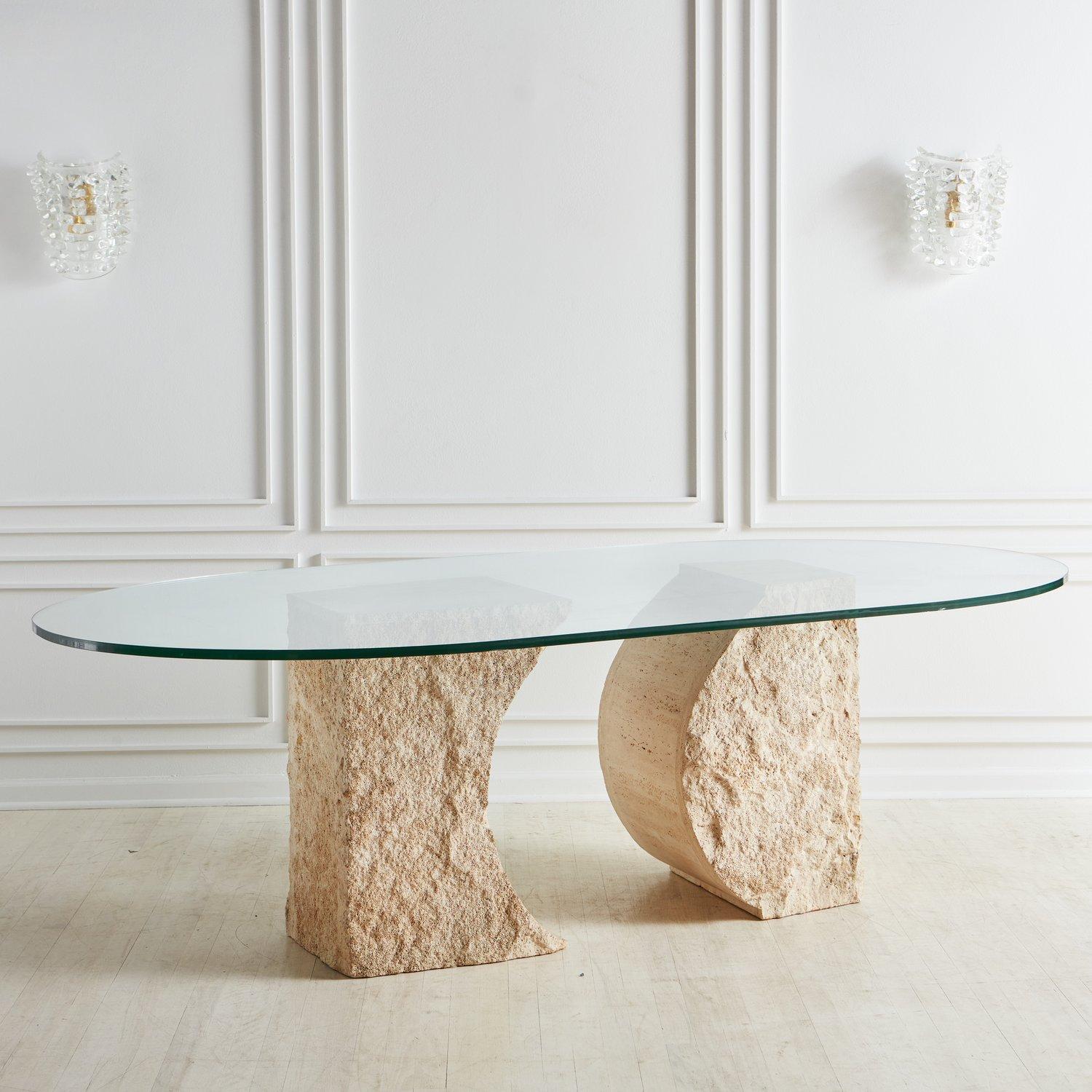 A beautiful dining table designed by Willy Rizzo in 1975. The base of this table consists of two carved solid travertine blocks with porous, textural details. The base supports a large. 75” thick oval table top. Signed ‘Willy Rizzo’ at the base of